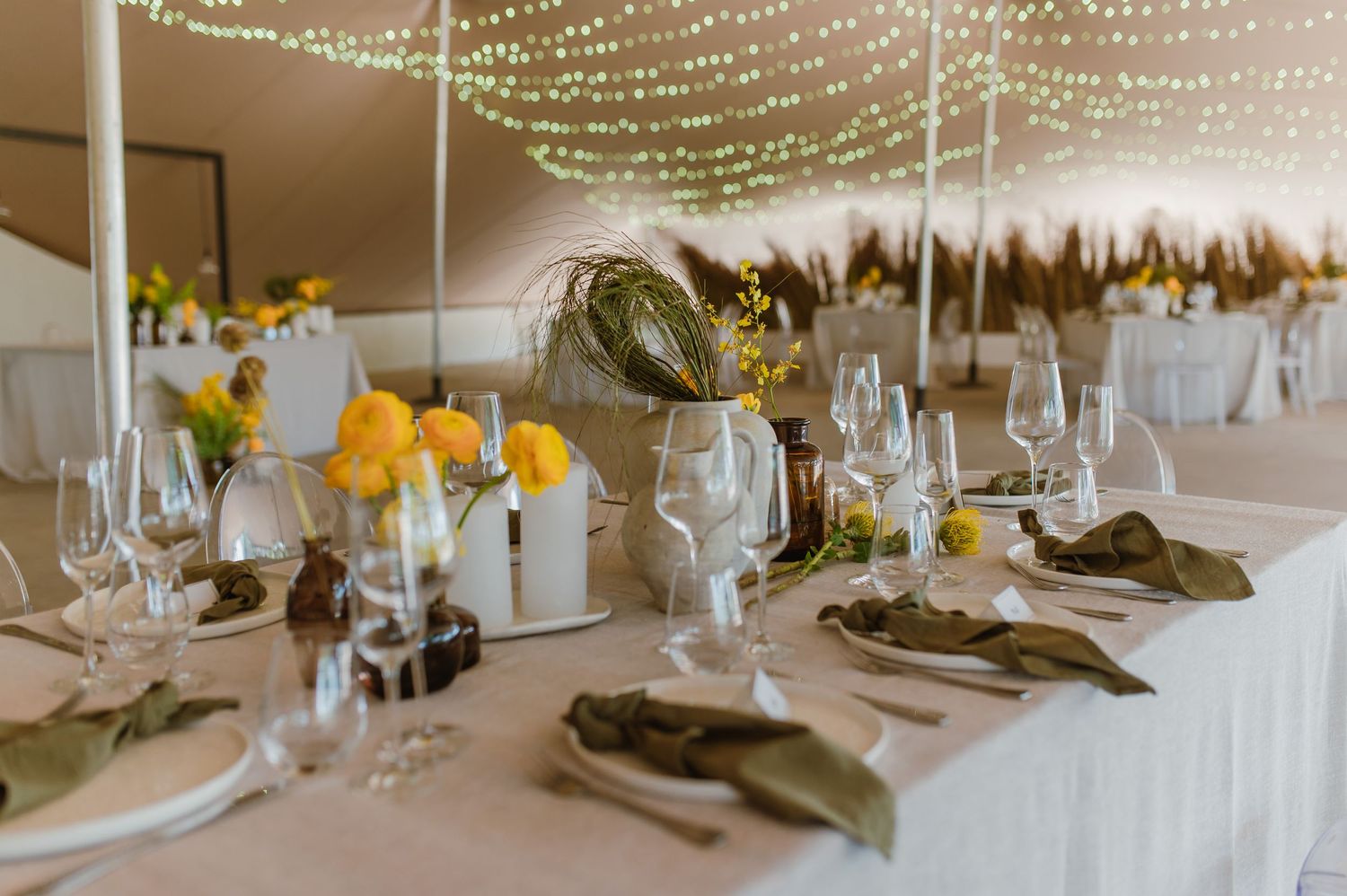 Wedding reception tables with elegant place settings under twinkling string lights.