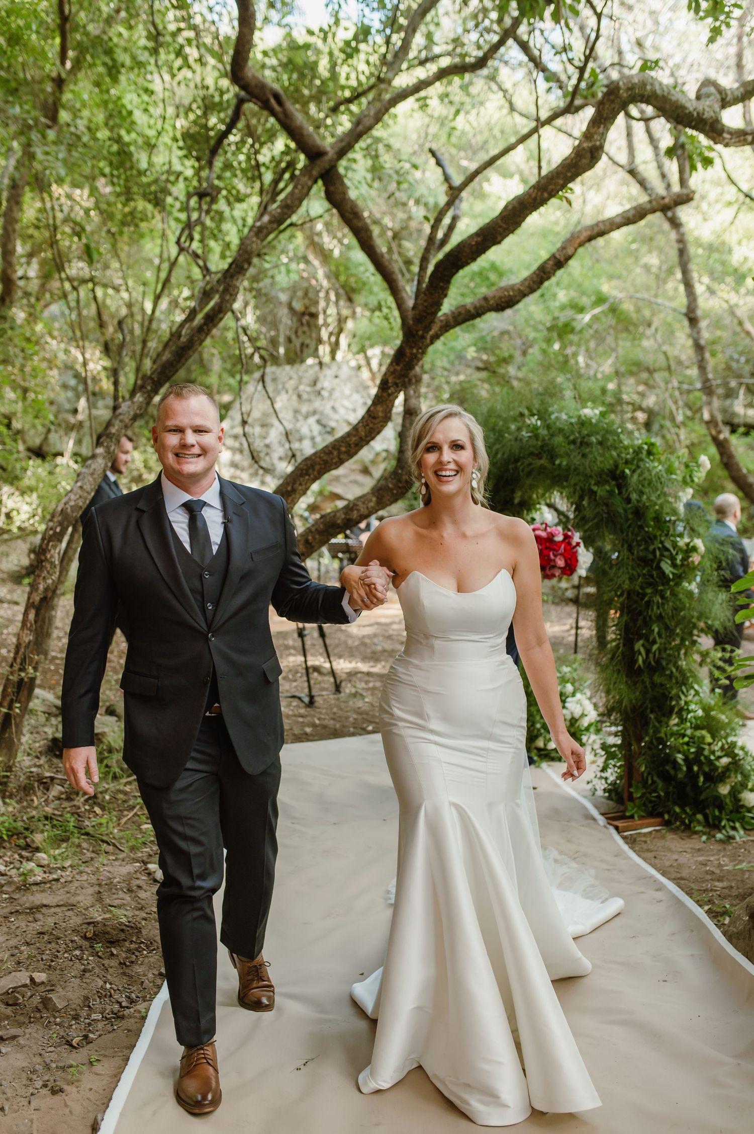 Couple walks hand in hand along a garden path during their outdoor wedding celebration.