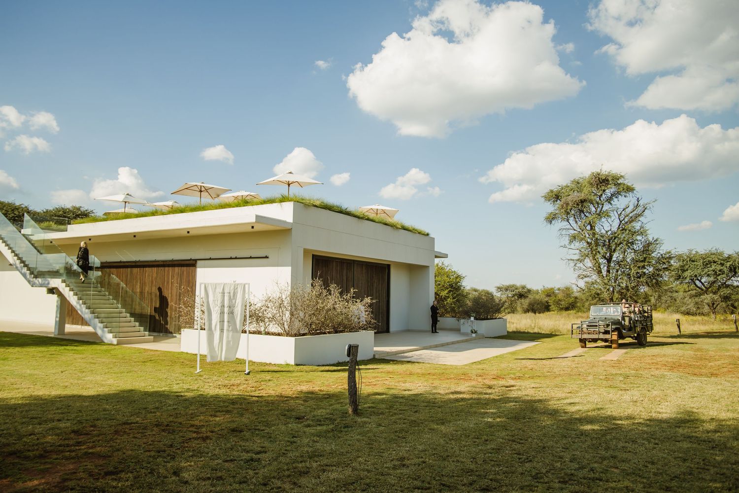 Panoramic view of a modern white wedding venue building set against rolling hills and blue sky.