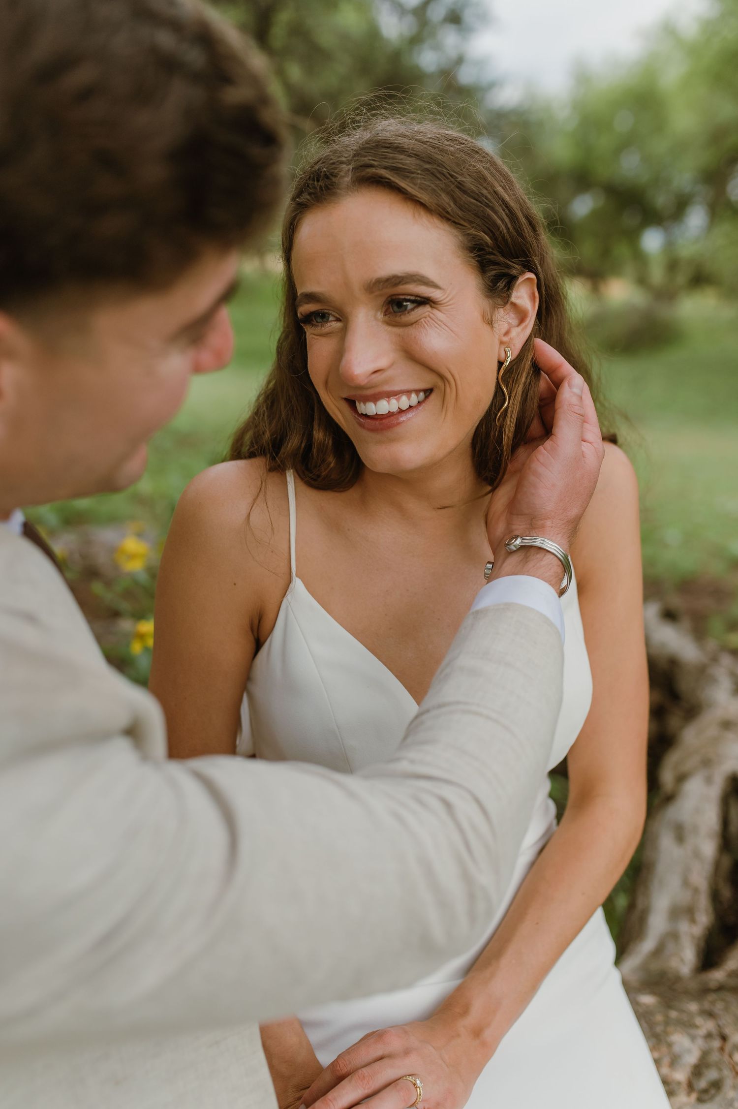 Intimate wedding moment captured under trees with soft natural lighting.