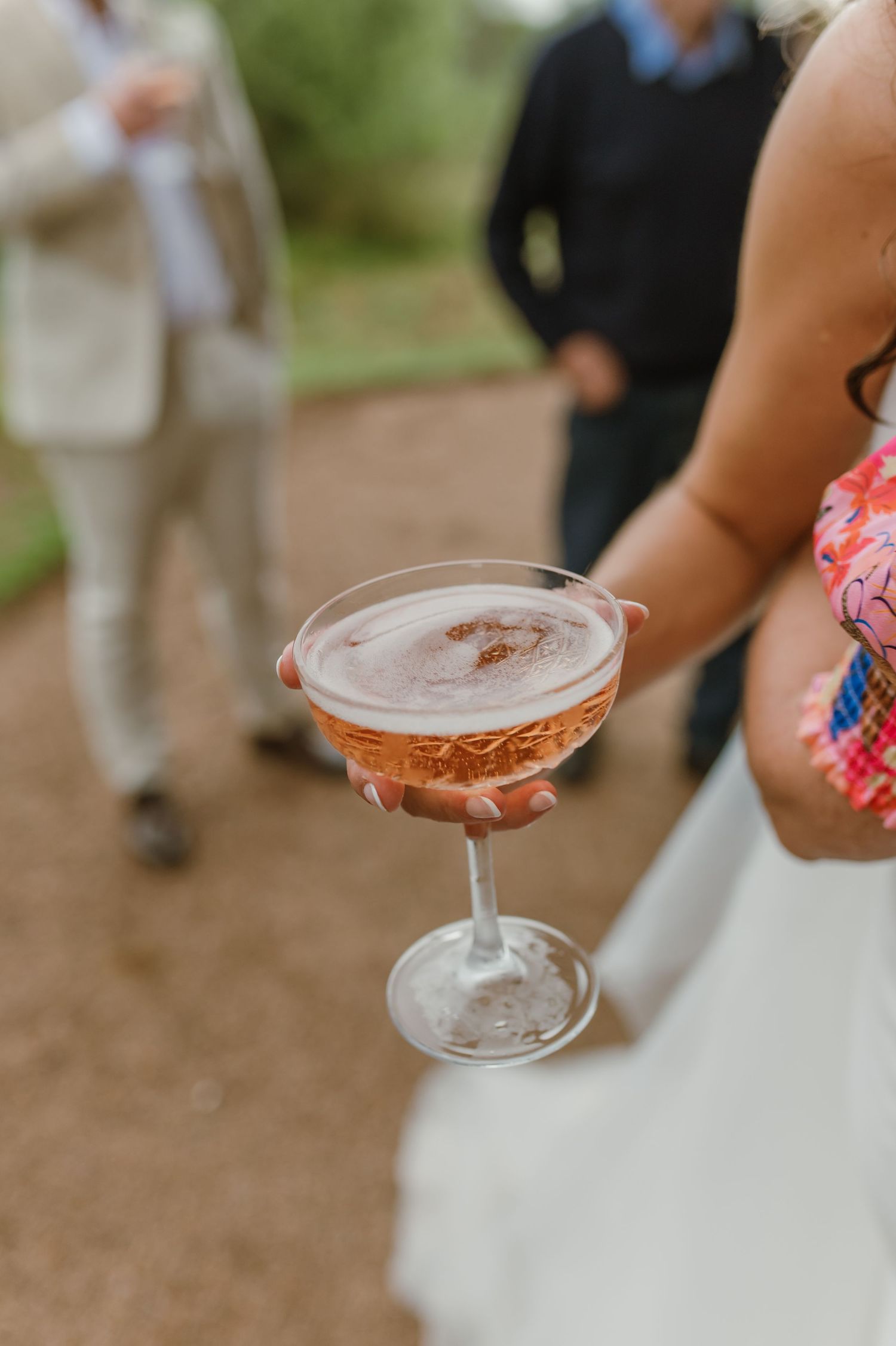Close-up of champagne cocktails being served at an outdoor wedding reception.