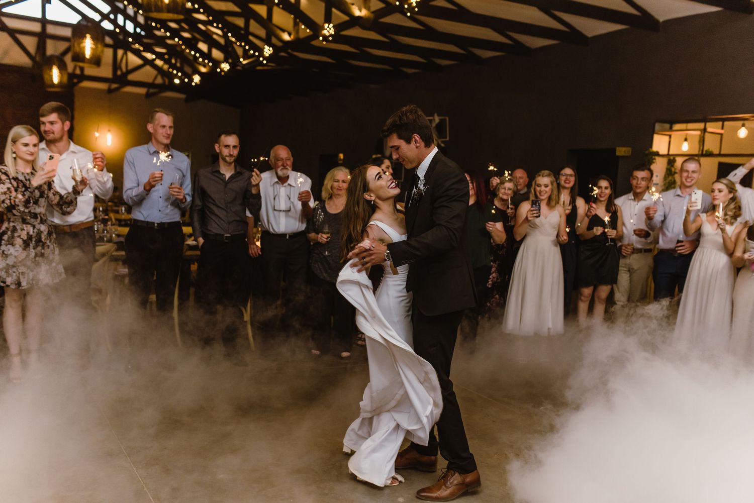 Wedding reception celebration with dramatic fog effects and guests dancing.