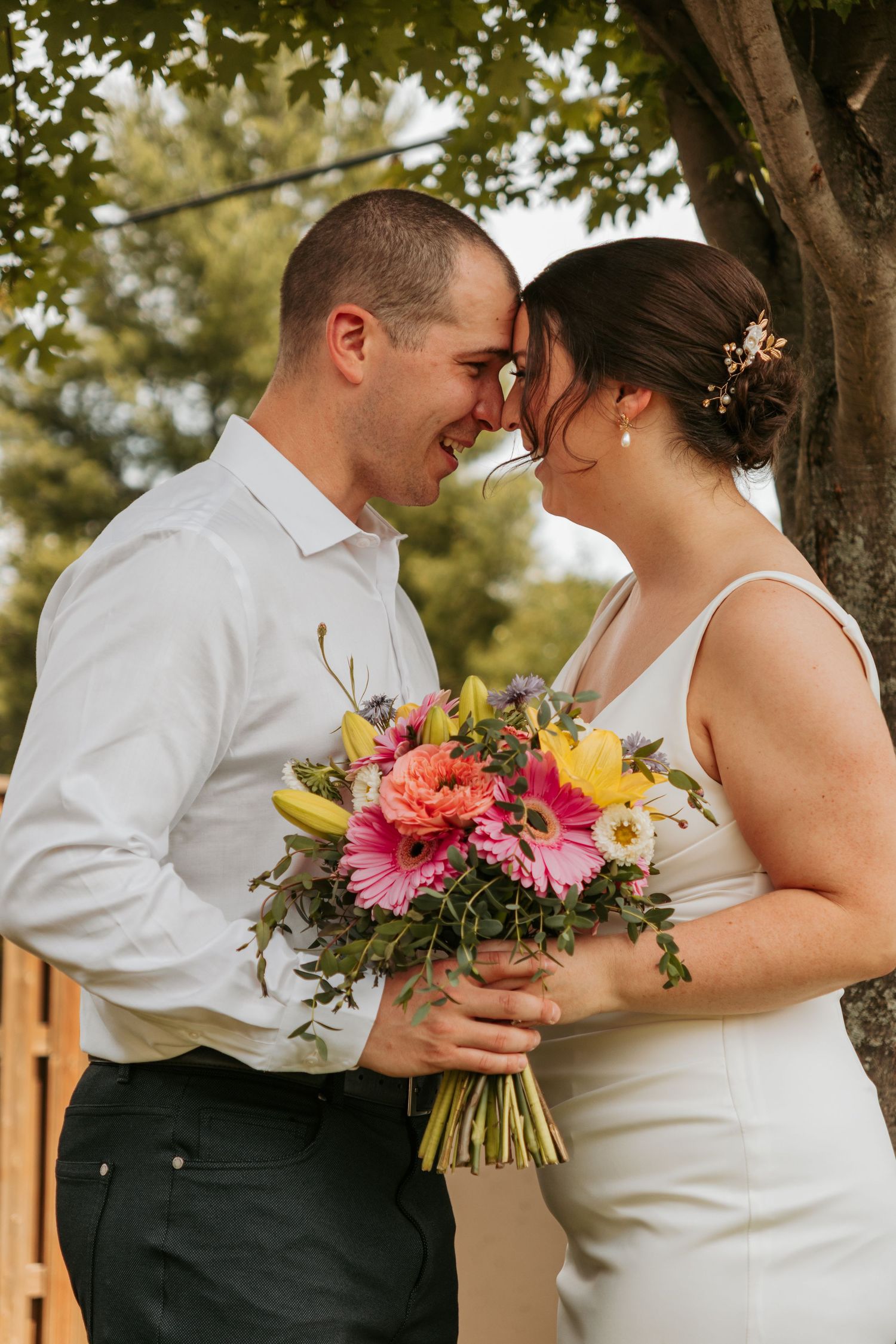 Romantic outdoor couple photos with bright floral bouquets under trees.