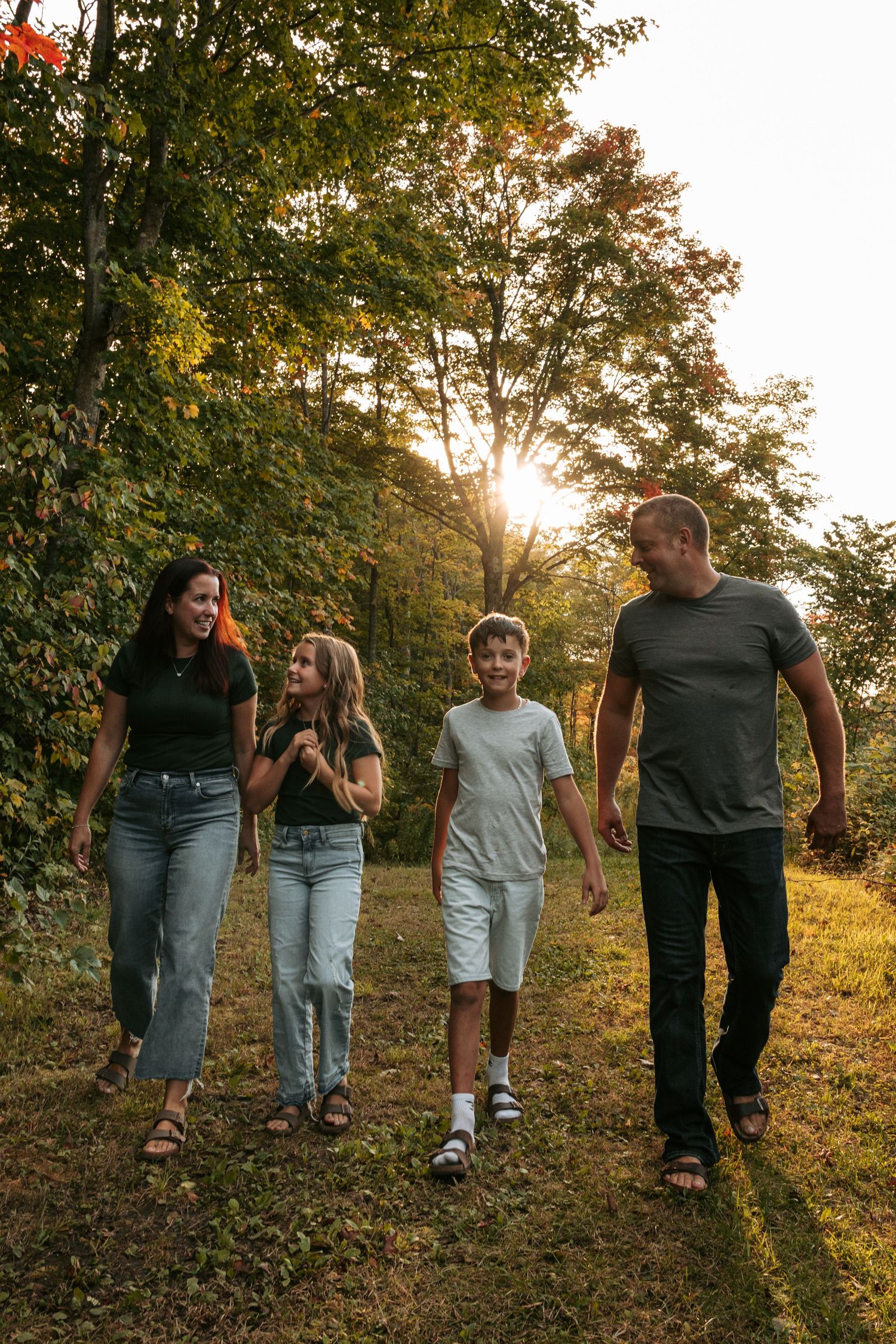 Group walking along a sunlit forest path during autumn with trees creating a natural backdrop.