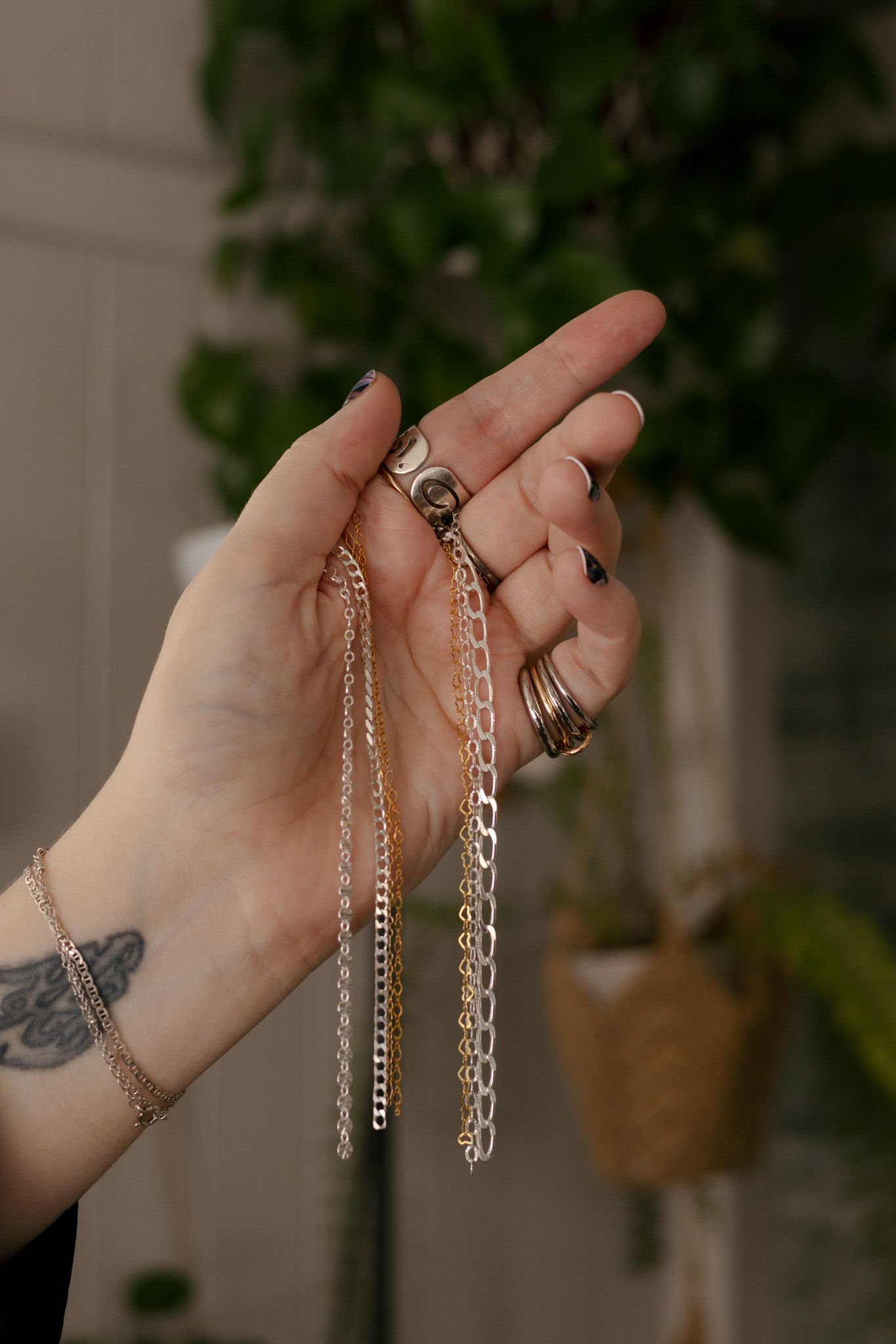 Hands holding and comparing different styles of silver jewelry chains against a natural background.