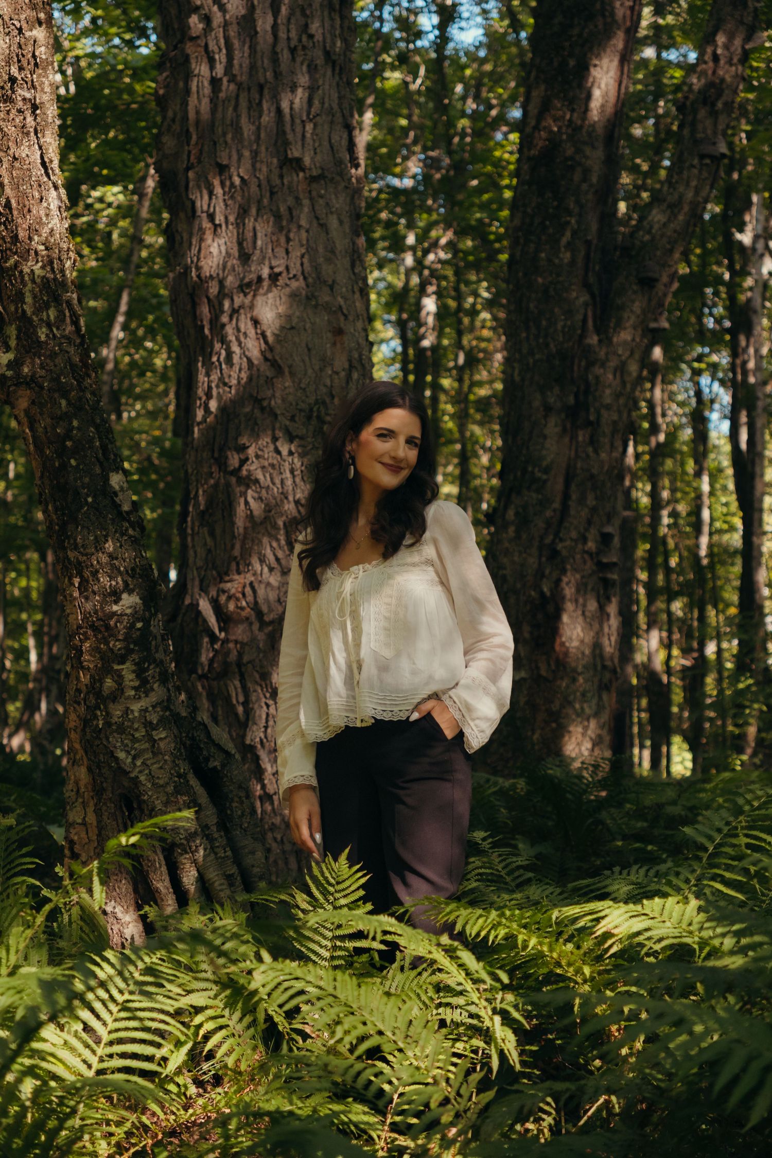 Sunlit forest scene with vintage-style clothing and natural fern undergrowth.