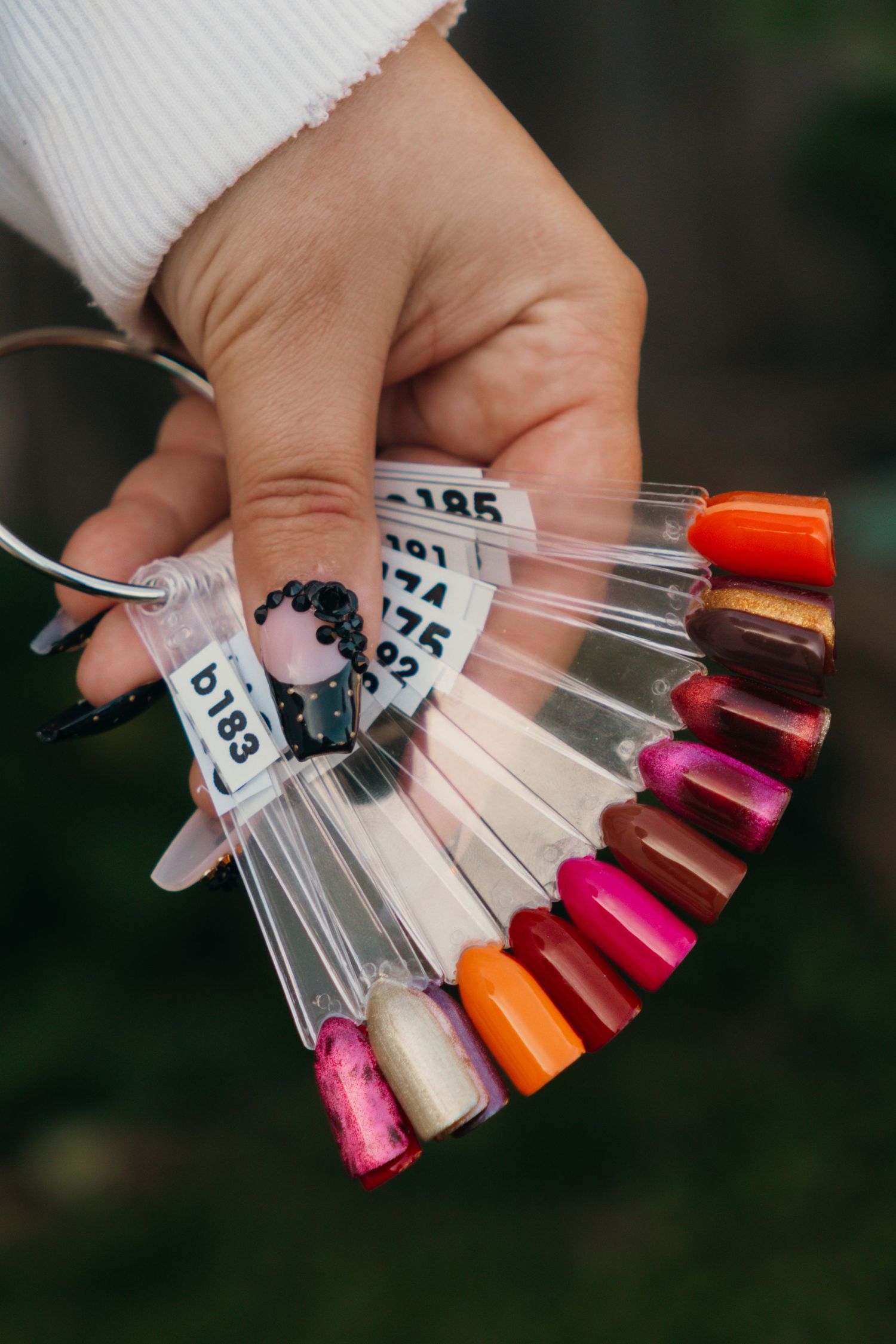 Colorful nail polish swatches displayed on clear plastic tips arranged in a fan pattern.