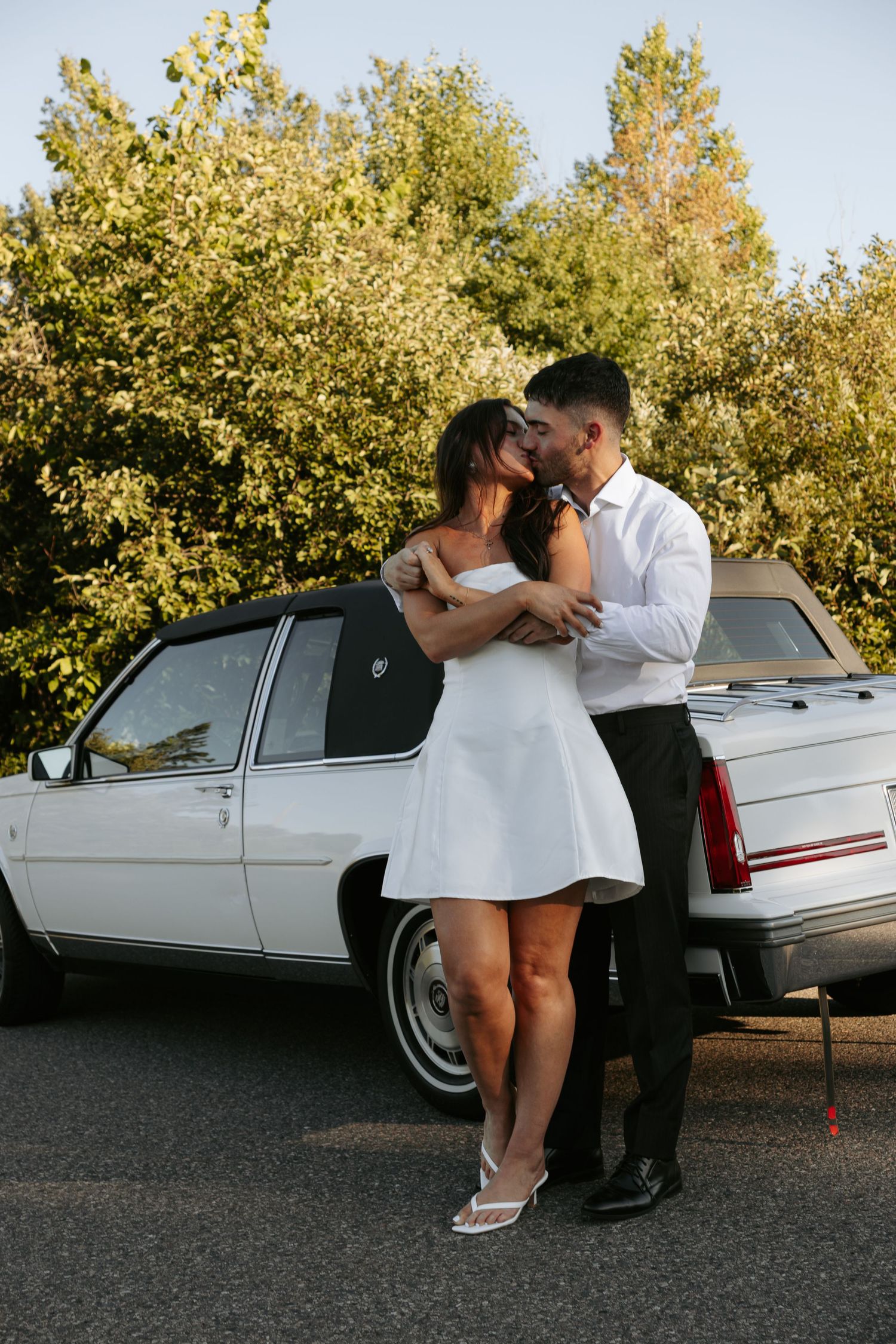 Intimate couple's photoshoot by vintage white Cadillac during golden hour.