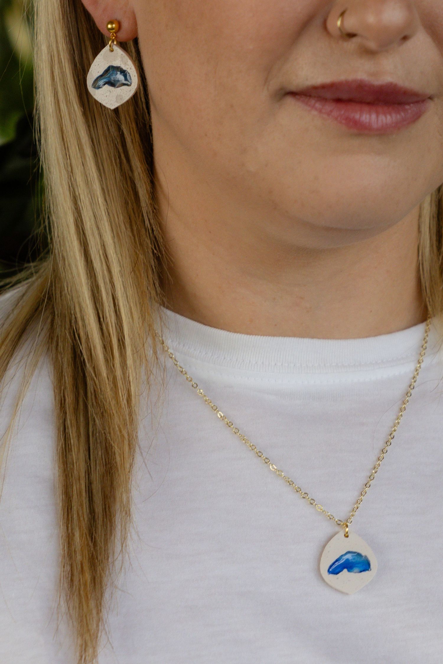 Matching whale-themed jewelry set with earring and necklace on white clothing.