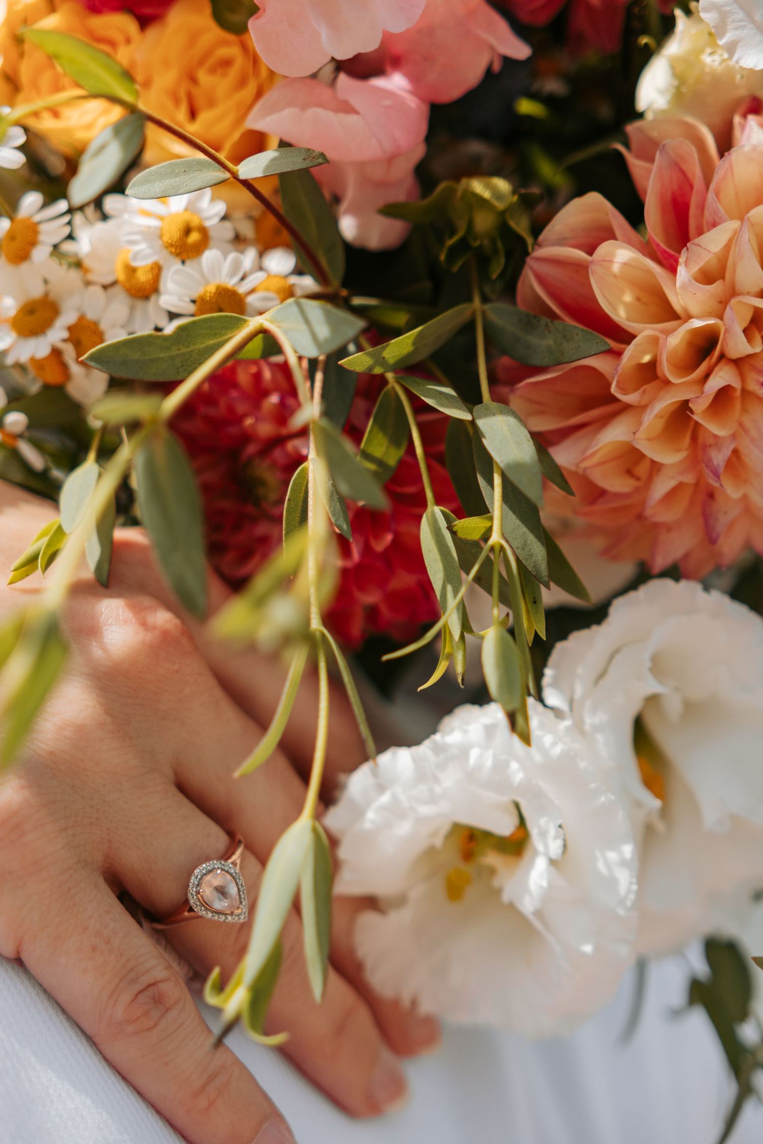 Close-up of peach and pink wedding bouquet with delicate flowers and greenery.