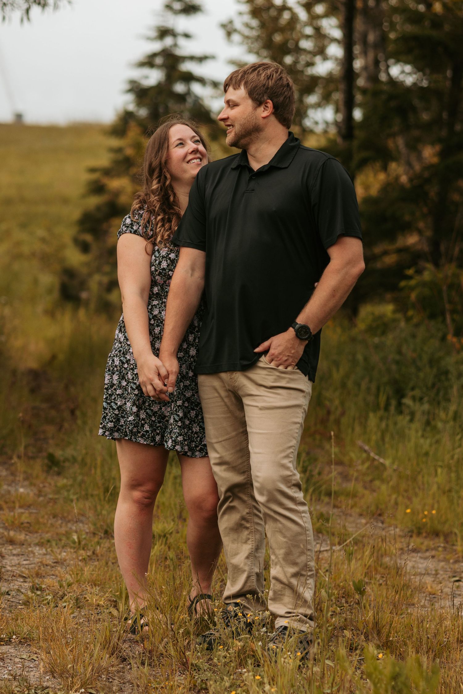 Couple laughing together in a field during golden hour photography session.