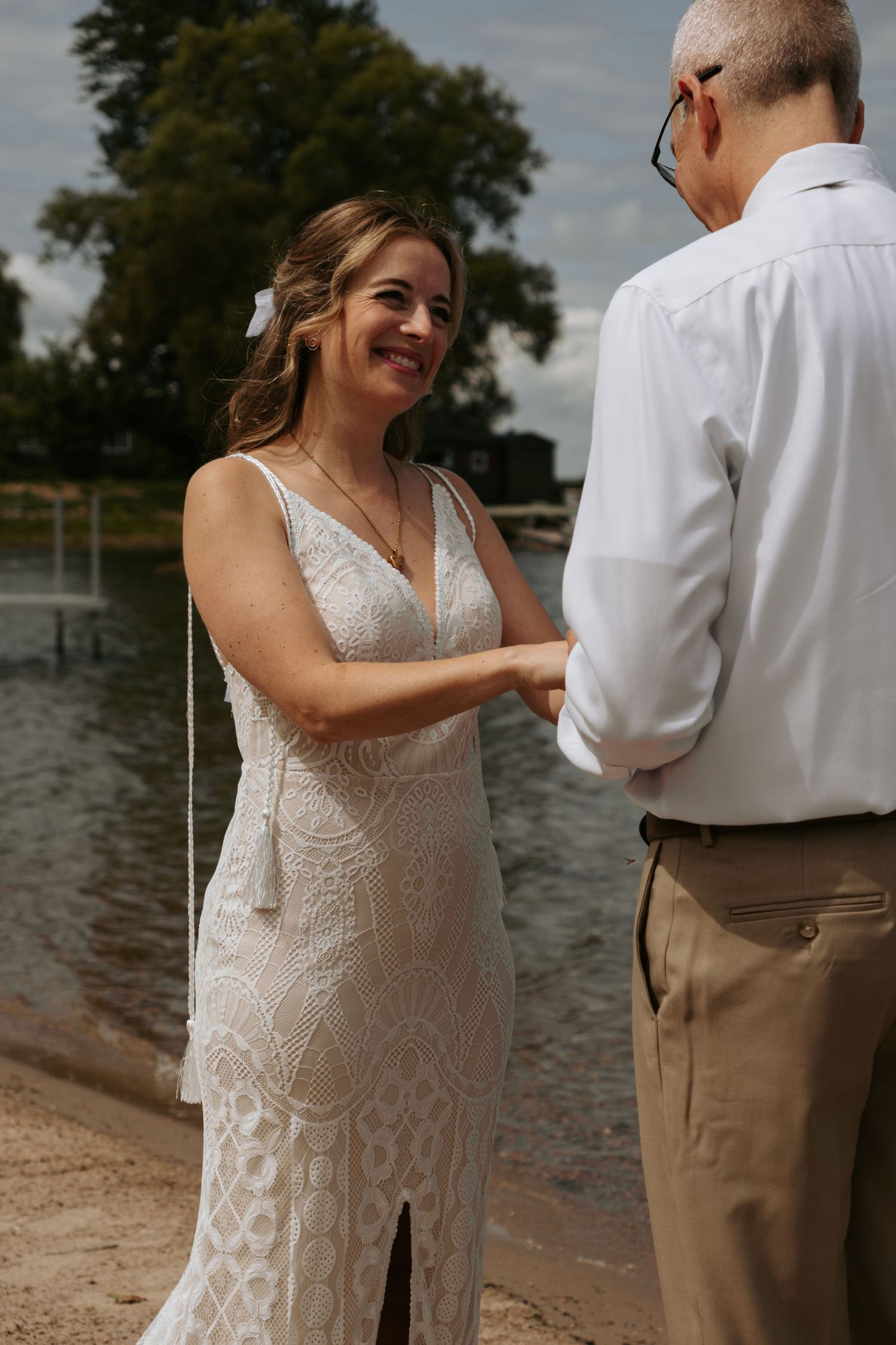 Couple in wedding attire sharing a romantic moment by the waterfront.
