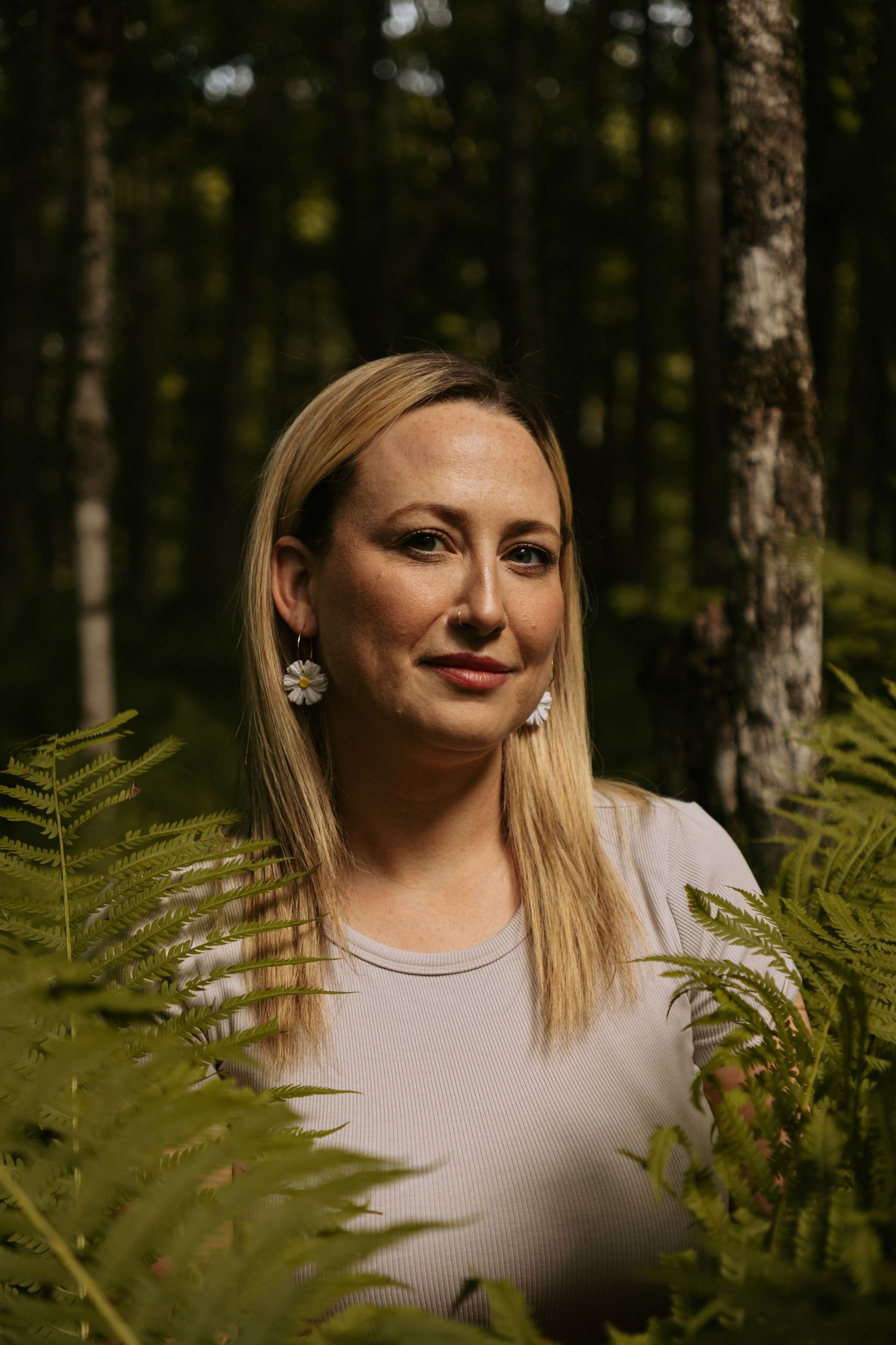 Portrait of someone in light clothing surrounded by ferns in a forest.