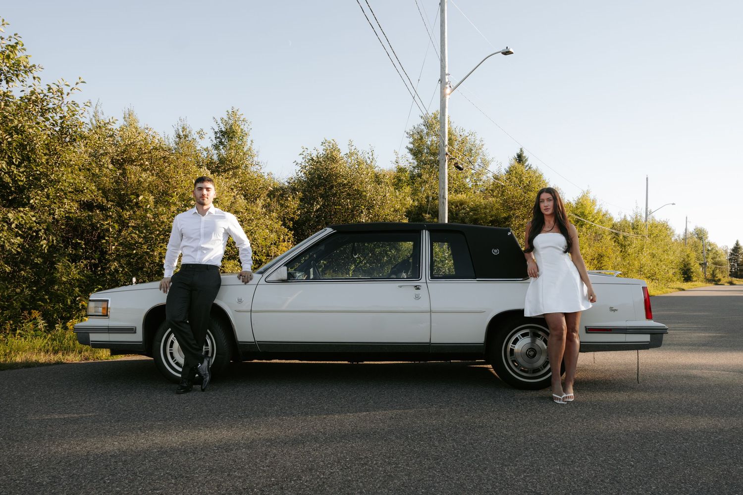 Classic white Cadillac photographed from side angle on asphalt road.