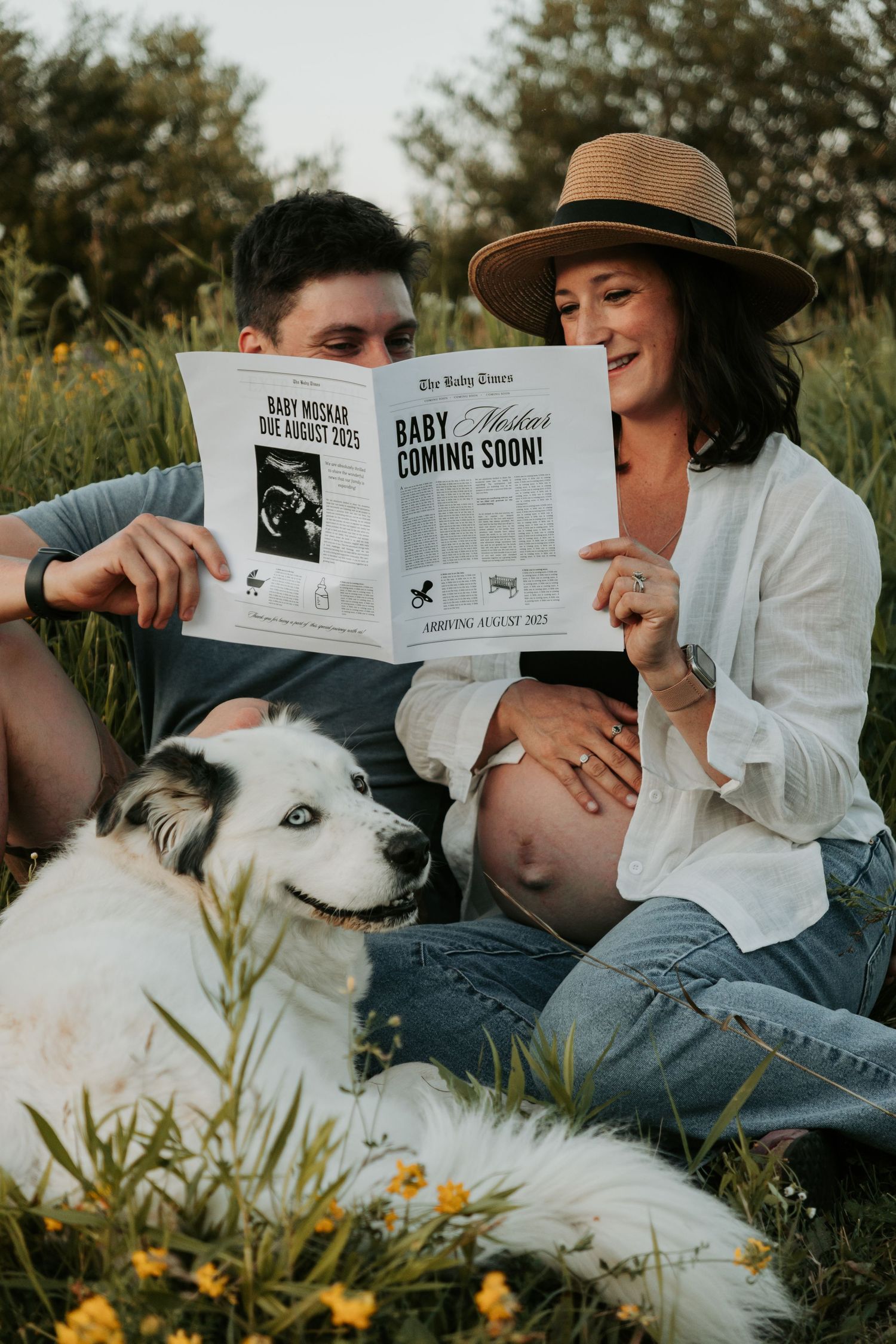 Couple relaxing outdoors with their white dog while reading a magazine.