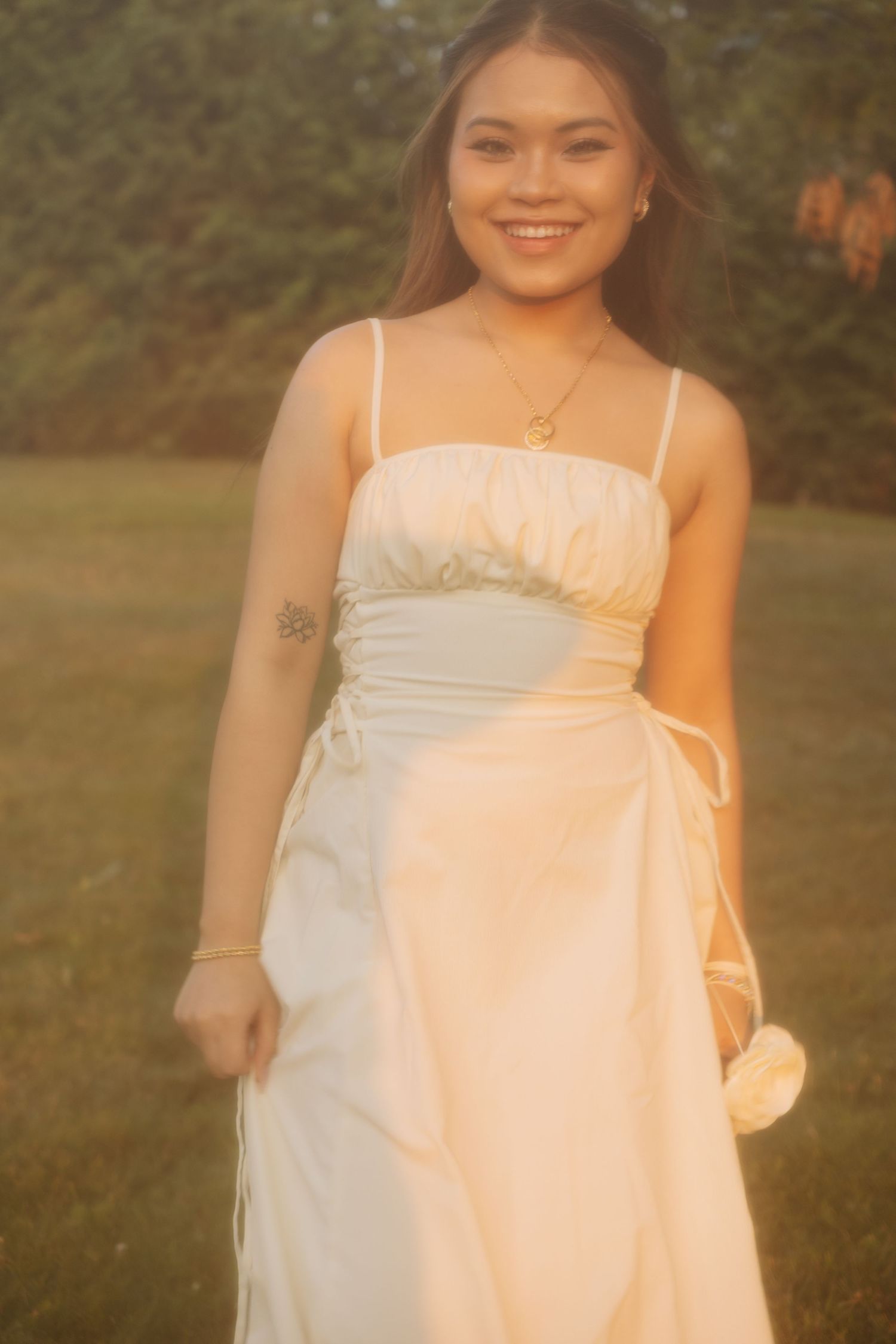 A warm sunset portrait of someone in a white sundress with delicate jewelry and natural styling.
