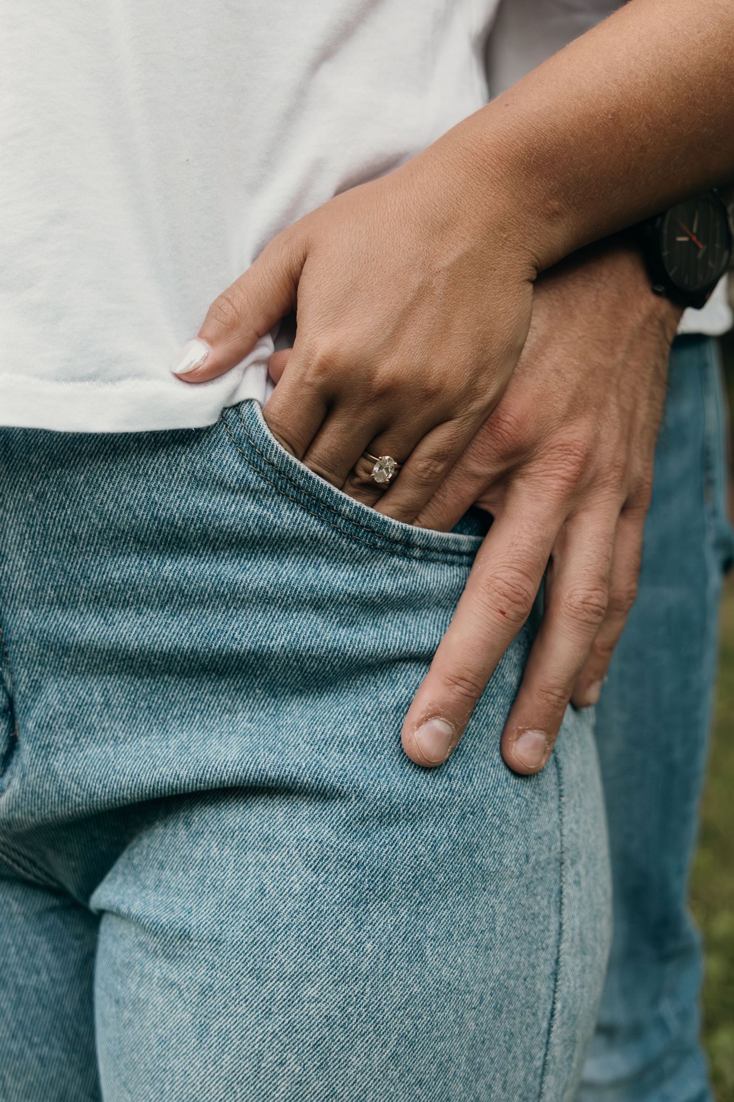 Close-up of hands resting on denim jeans showing ring details.