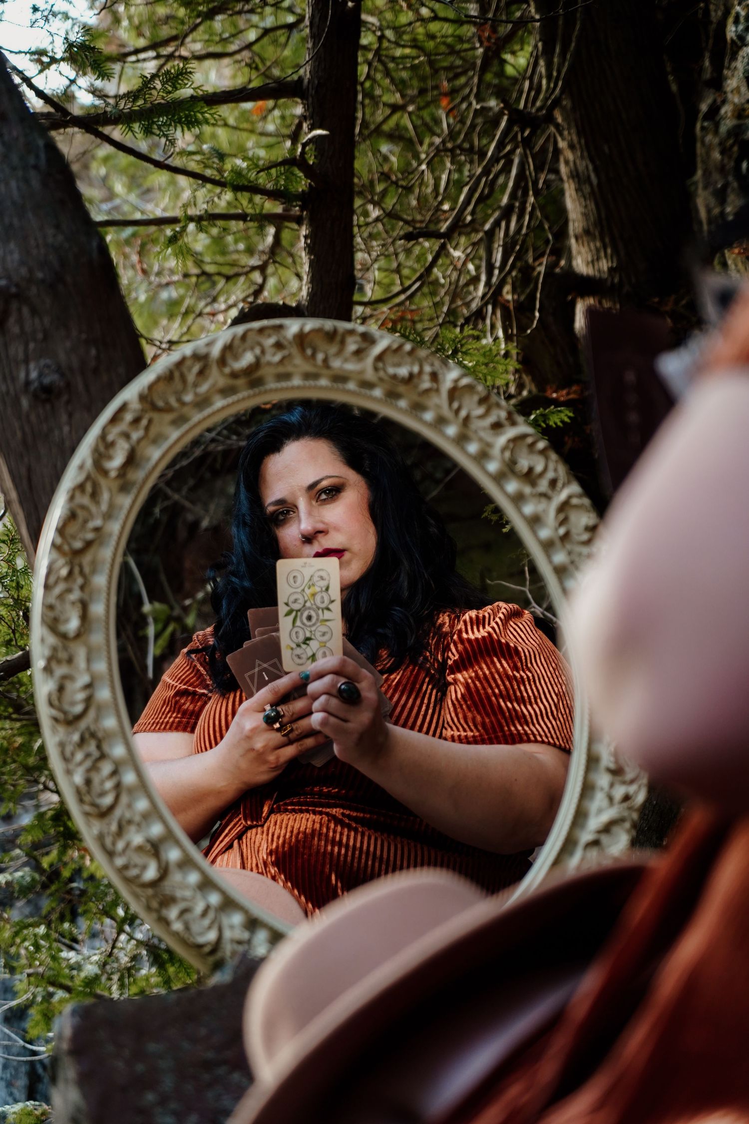 Ornate vintage mirror reflecting through trees in outdoor setting.