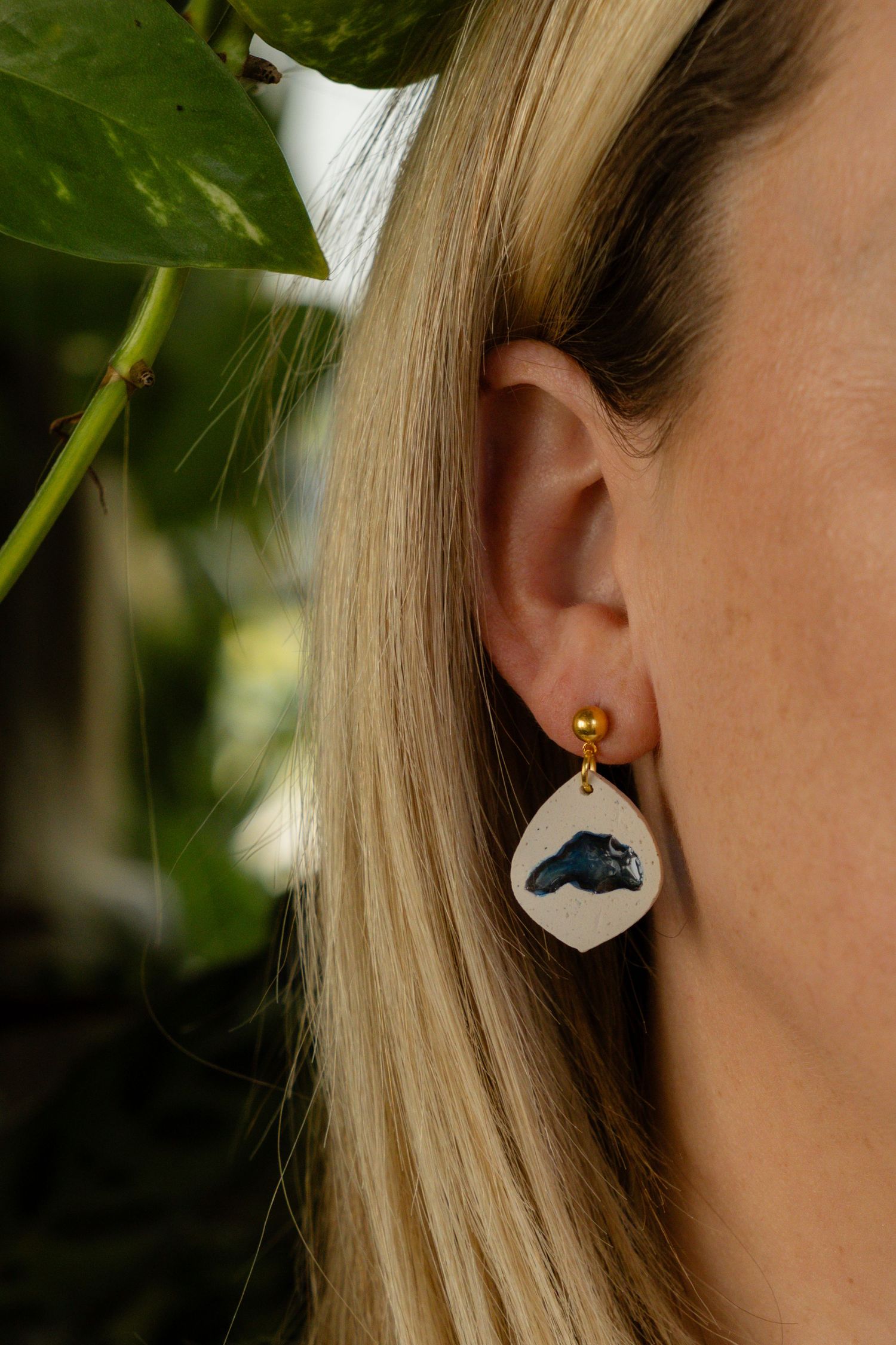 Close-up of an ear wearing a white and blue whale-themed earring.