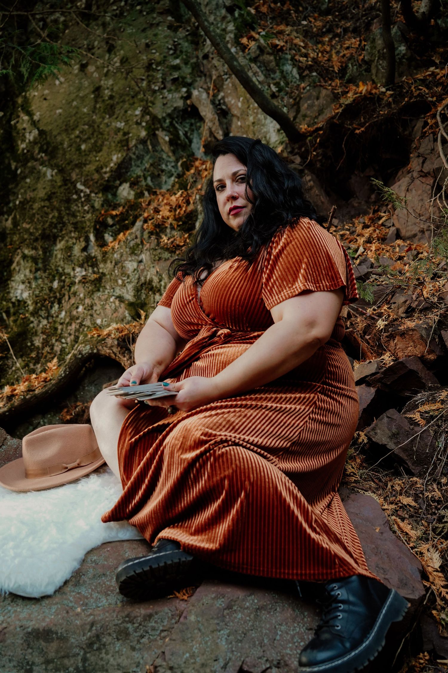 A moody autumn photoshoot featuring a brown corduroy dress against a natural rocky backdrop.