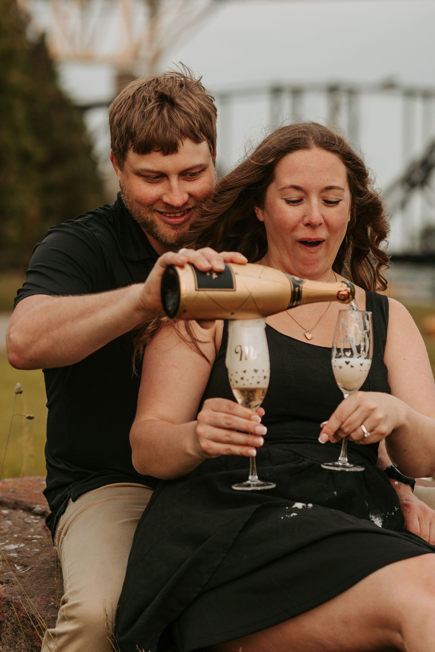 Happy couple sharing drinks and intimate moments during outdoor photo session.