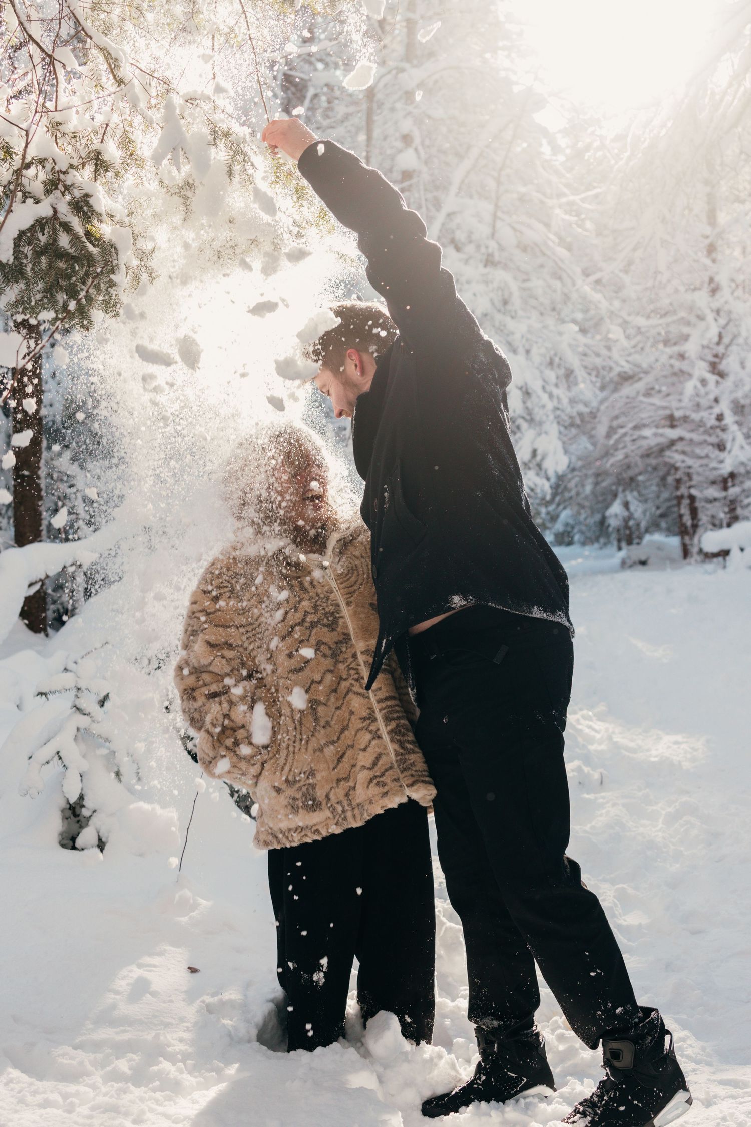 Two people enjoying a winter day together in a snow-covered forest.