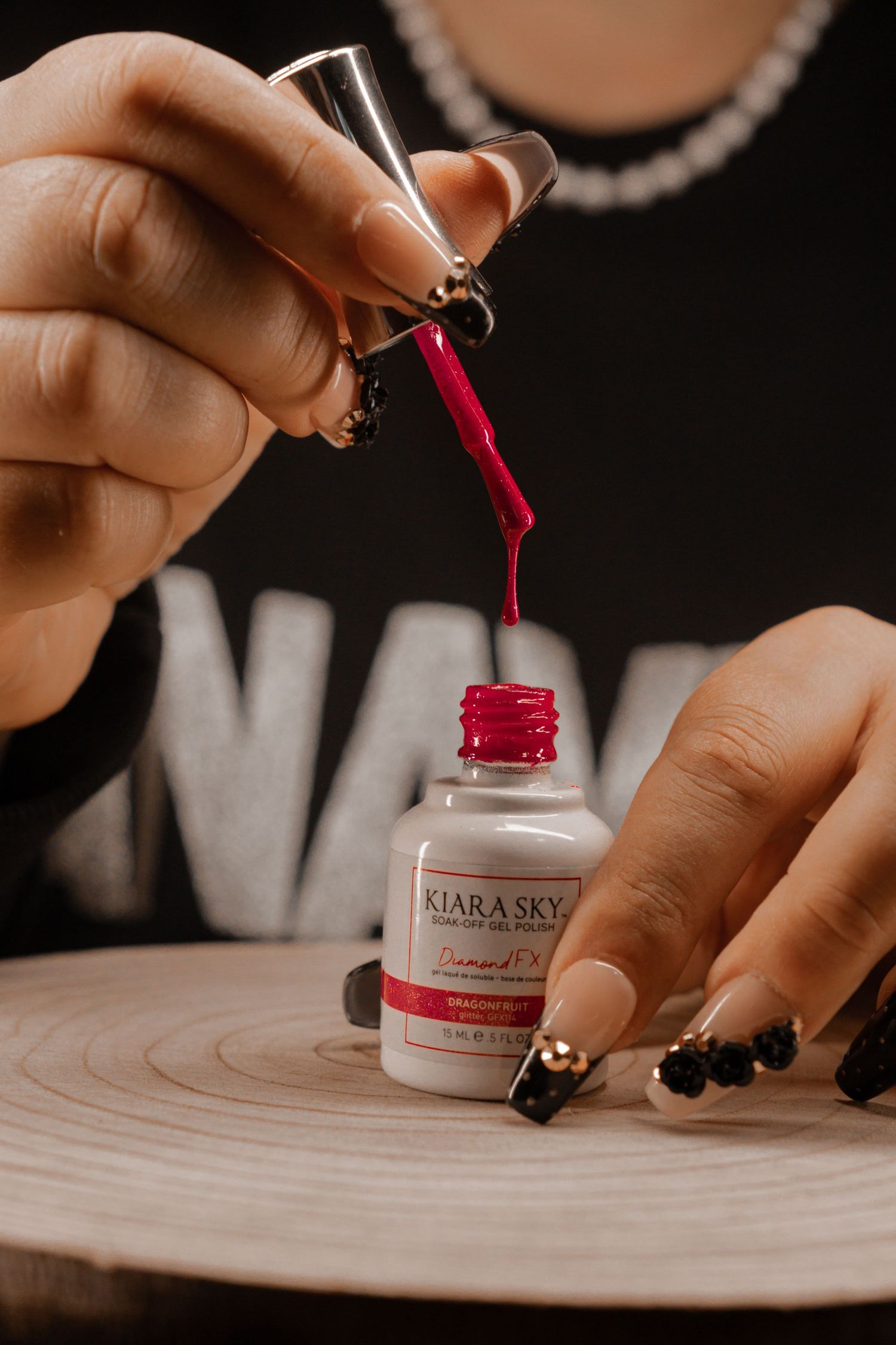 Opening a bottle of red nail polish and applying it to a surface.