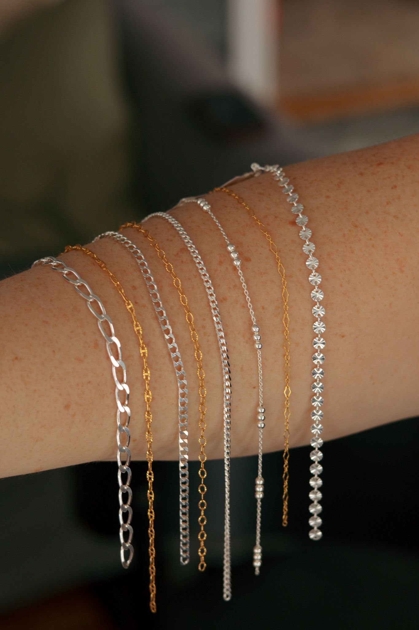 Collection of delicate gold and silver bracelets displayed side by side on an arm.
