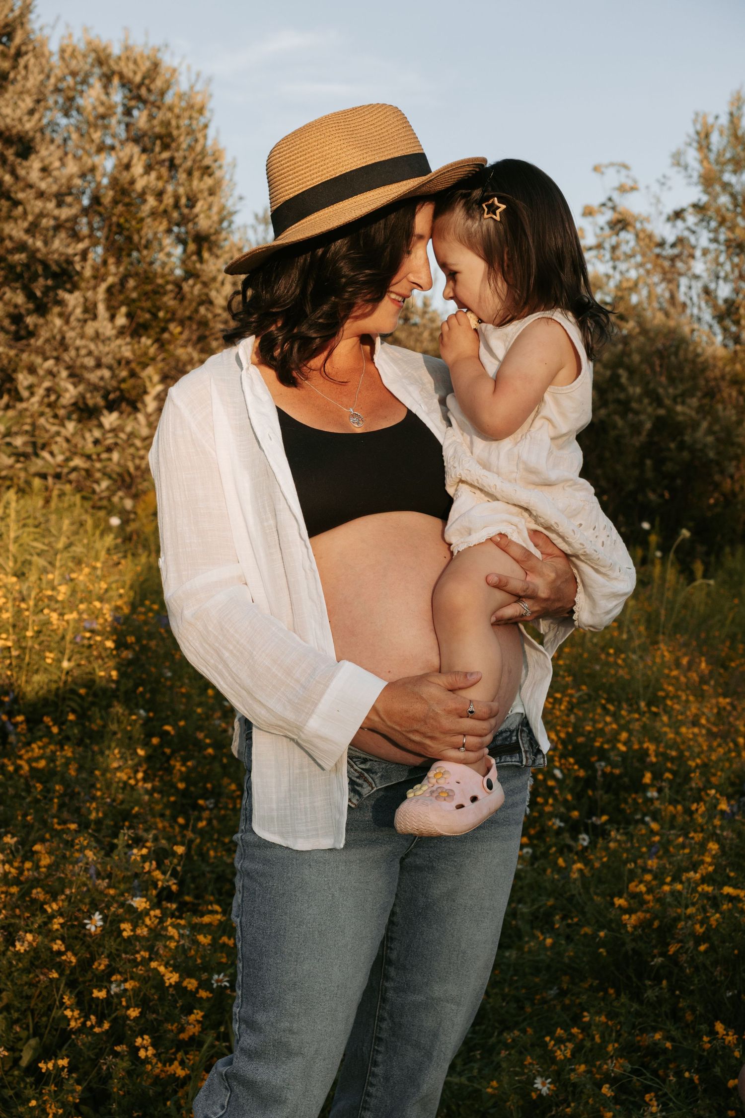 Maternity photos in a wildflower field during golden hour.