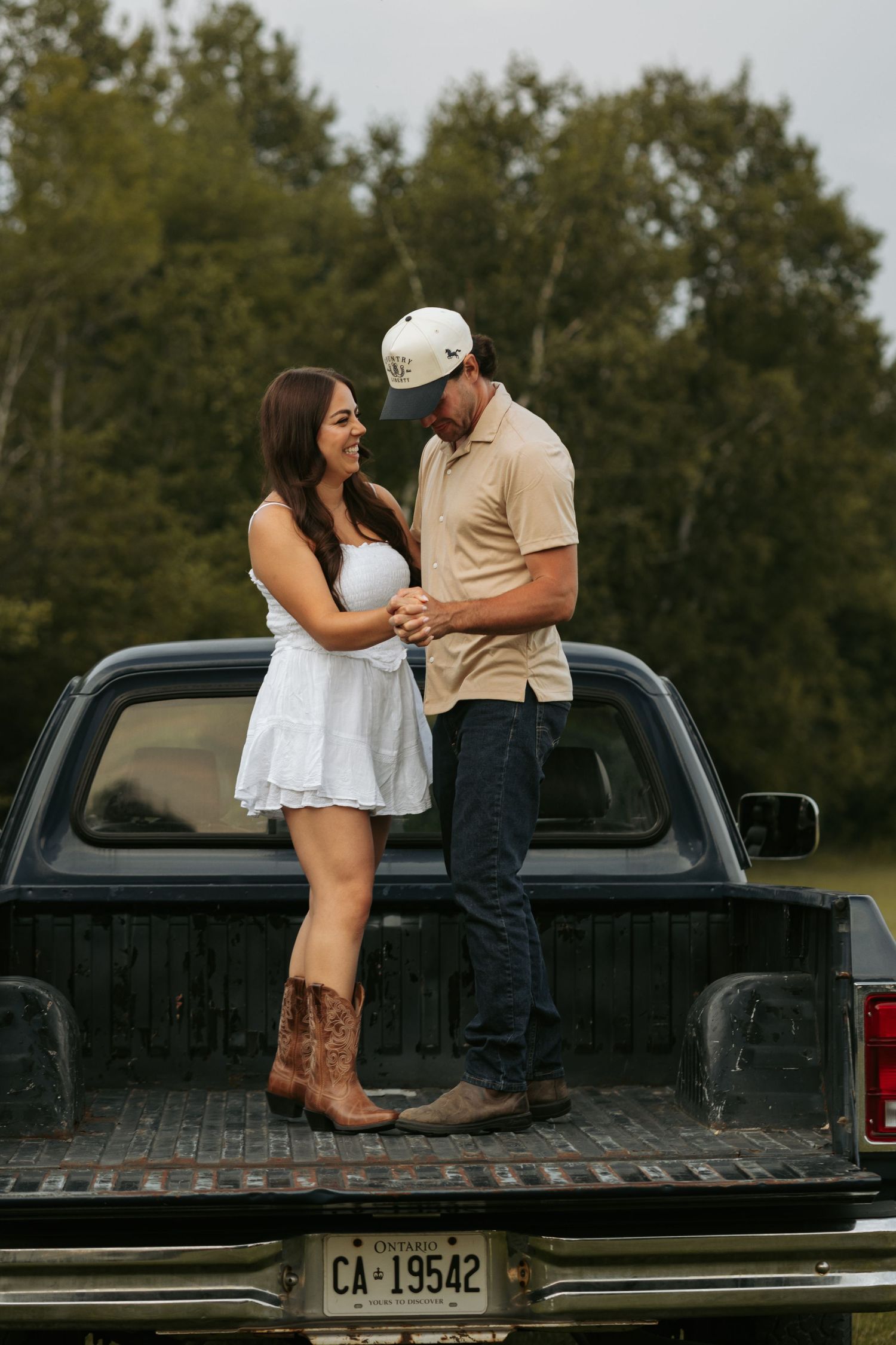 A couple shares a tender moment in the back of a pickup truck.