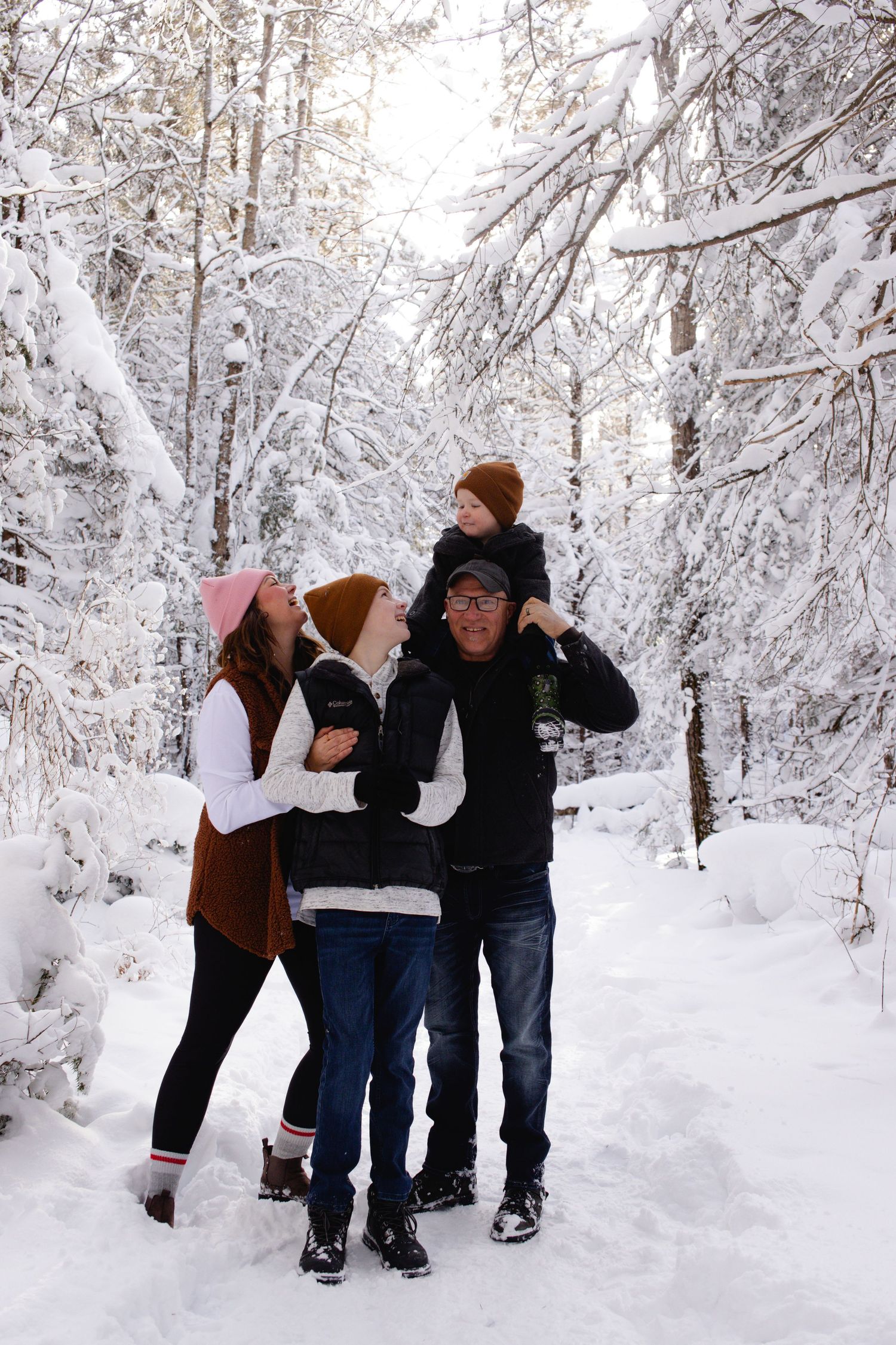 Friends celebrate a winter proposal moment in a snowy forest landscape.