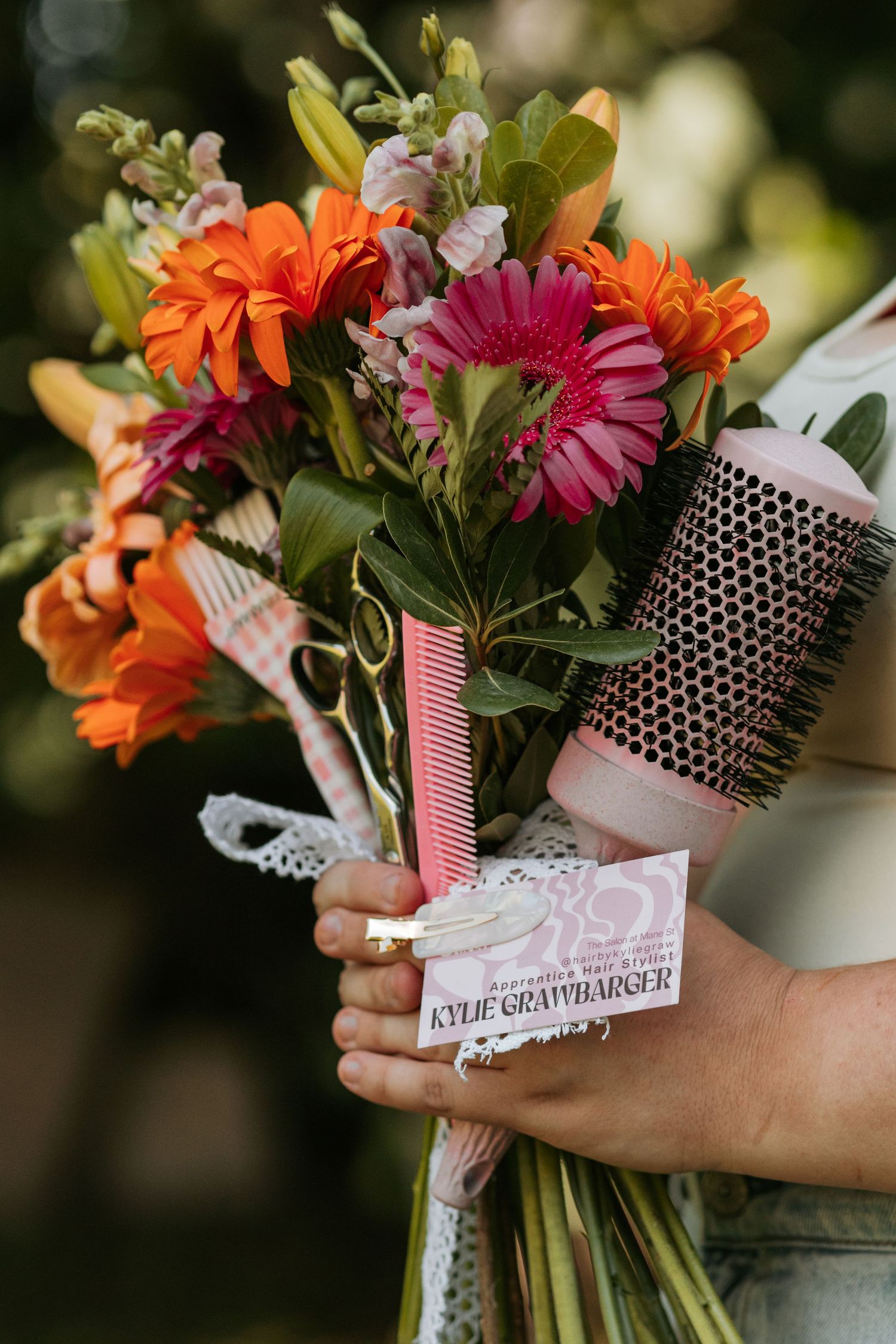 Bouquet of orange and pink flowers wrapped with decorative combs and ribbons.