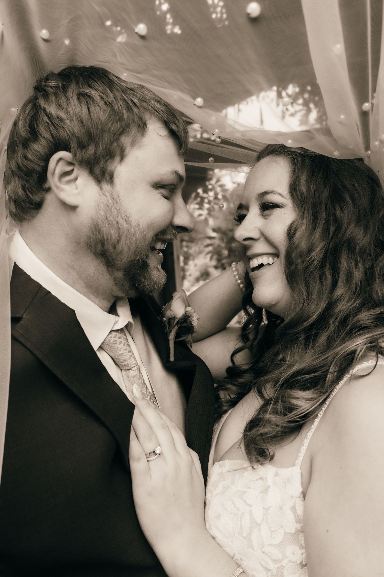 An intimate black and white portrait of a wedding couple sharing a tender moment.