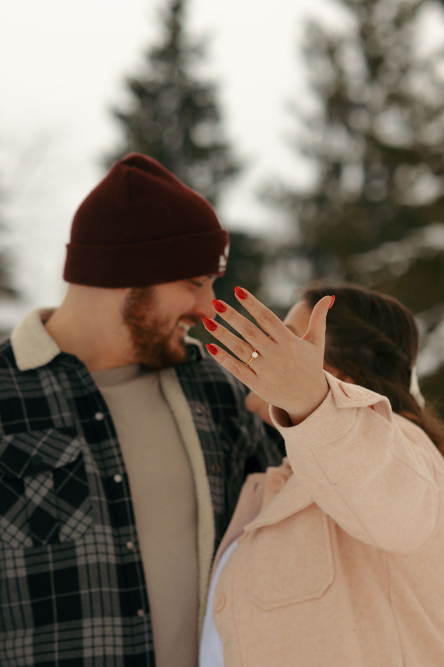 Winter scene with couple in plaid shirt and pink jacket showing emotional reaction.