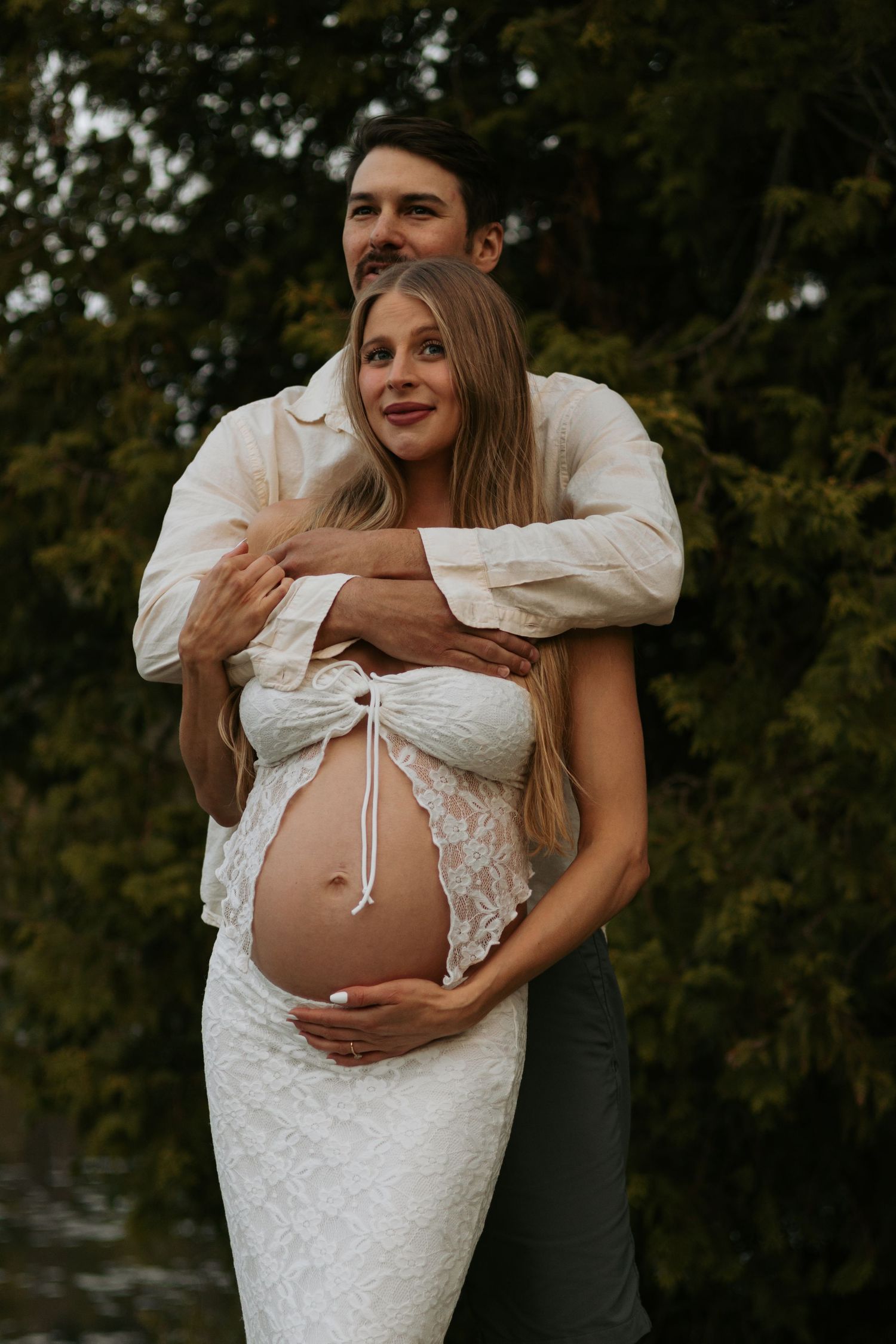 Beautiful maternity portraits showing couple's tender moments in outdoor setting.