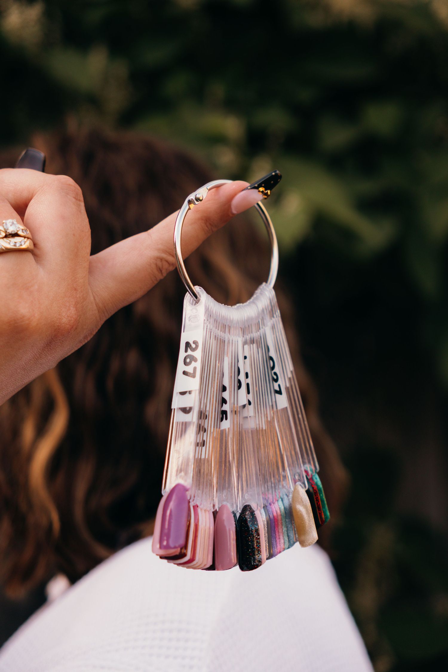 Close-up of artificial nails displayed in a fan pattern with pearl and rhinestone decorations.