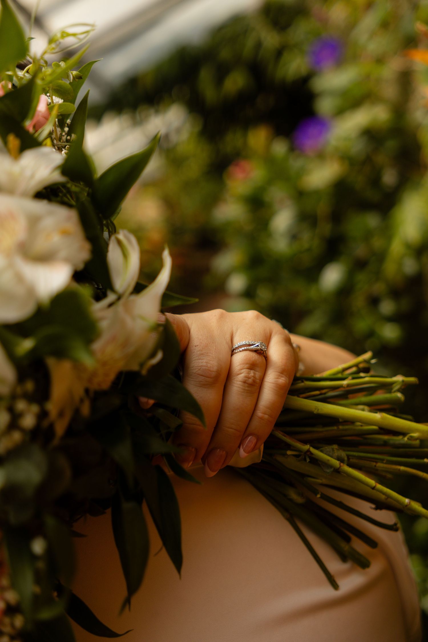 Close-up of hands holding a bridal bouquet with greenery.