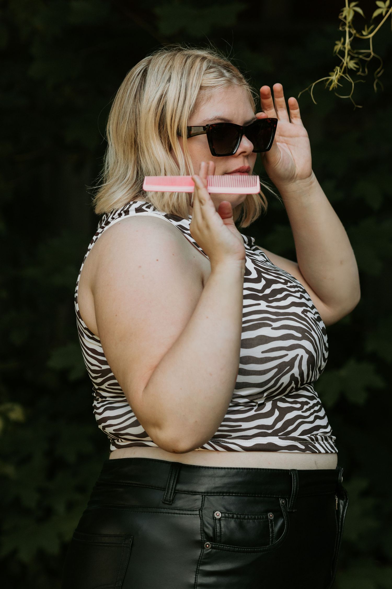 Person in zebra print top demonstrating hair styling techniques.