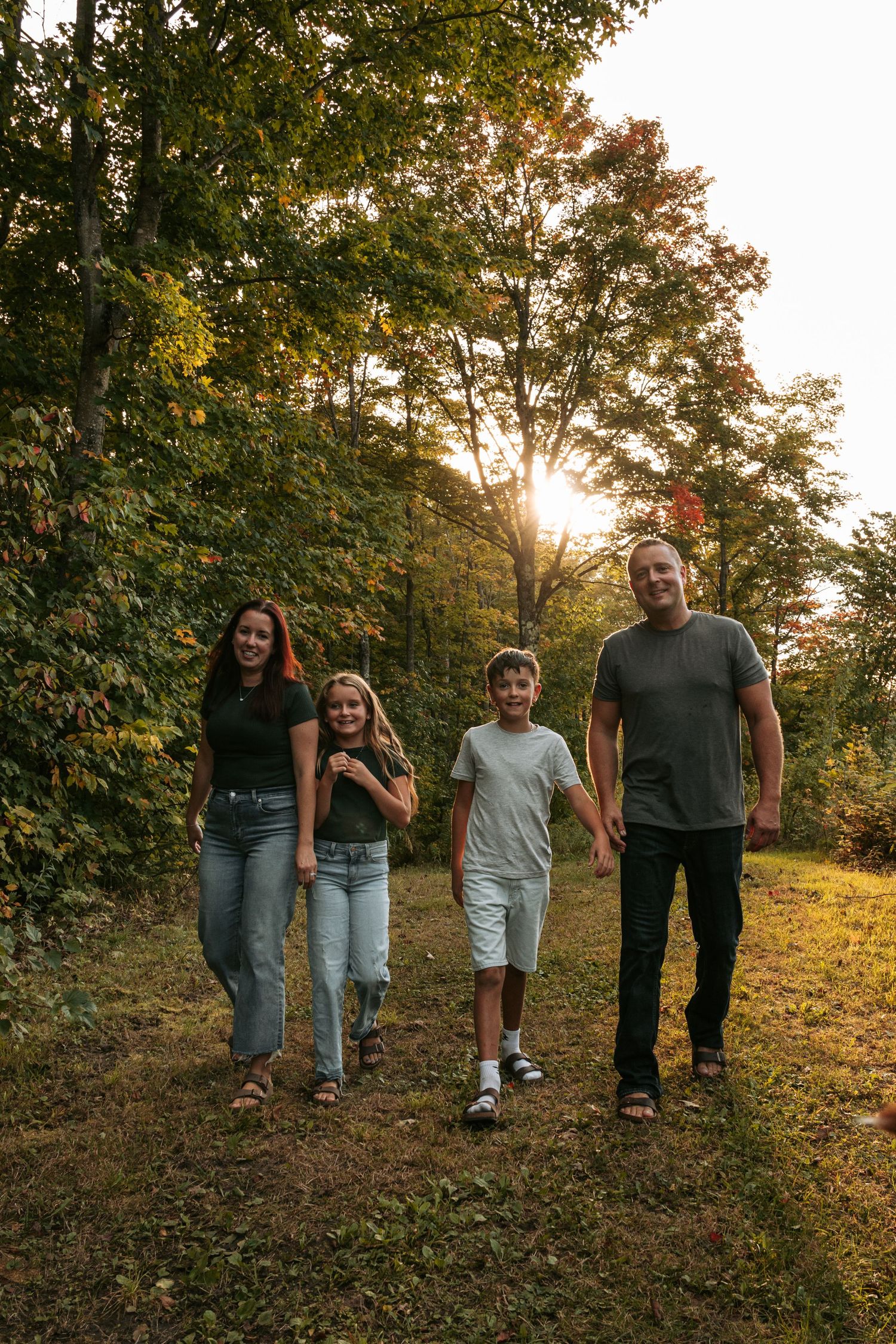 A family walking together on a nature trail during golden hour with trees in the background.