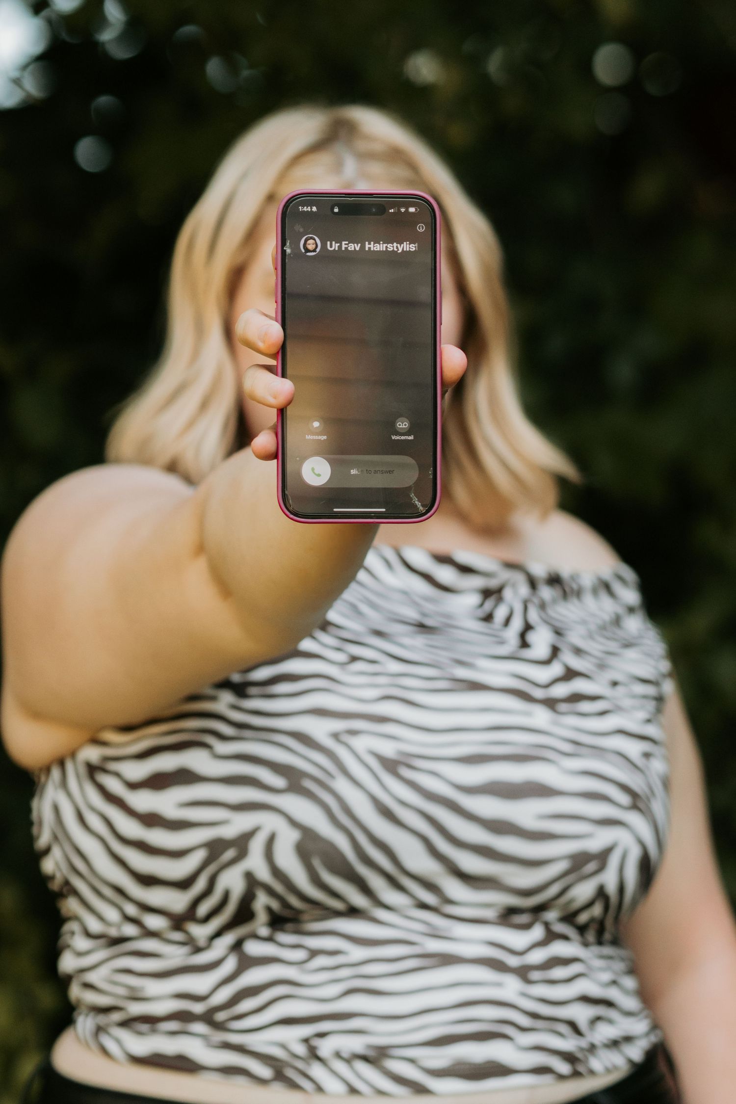 Person in zebra print showing phone screen during hair tutorial.