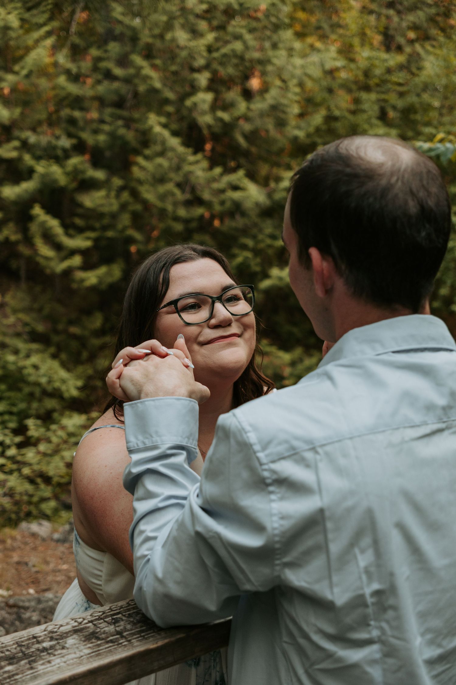 Couple shares intimate moment outdoors surrounded by lush greenery.