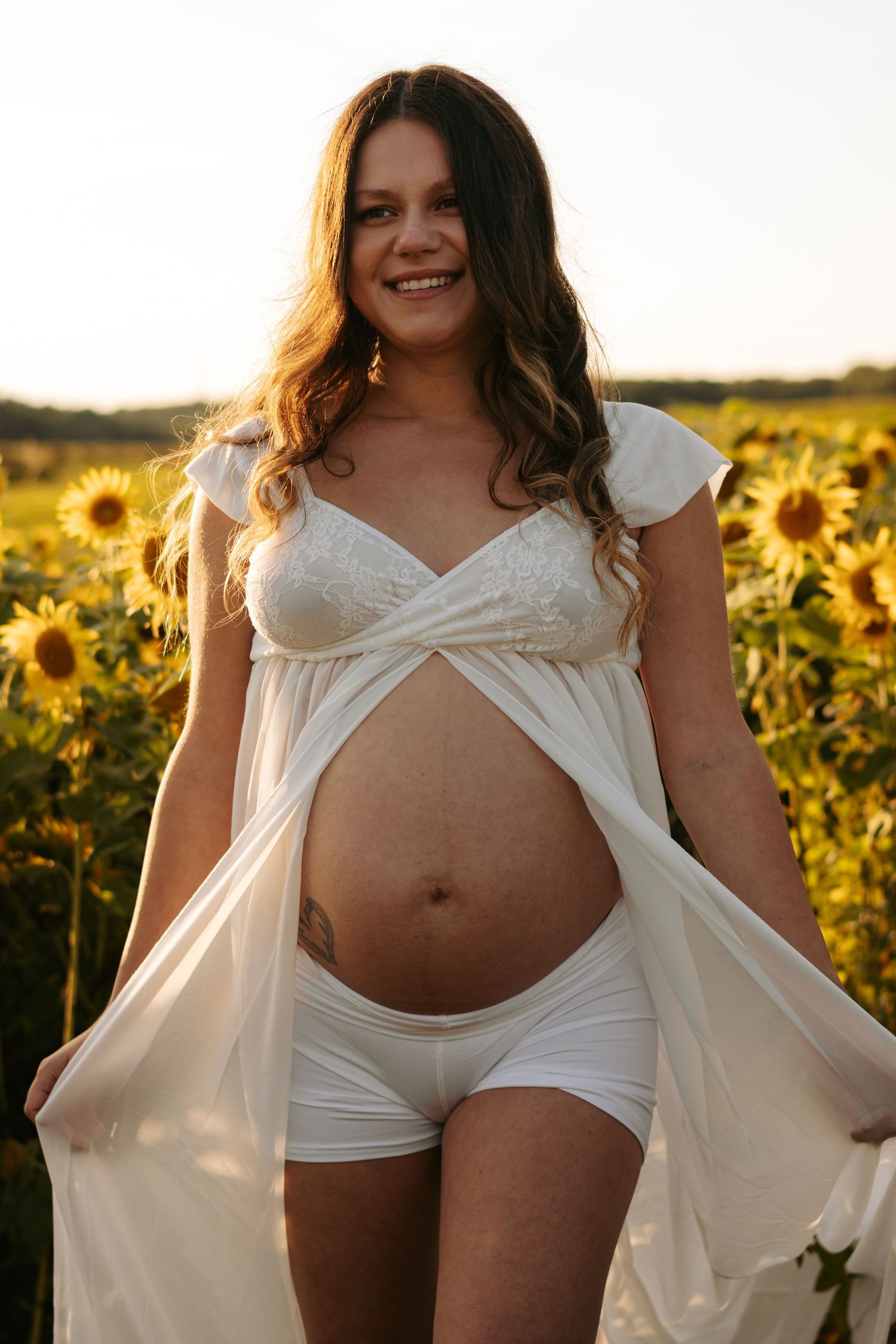 Maternity boudoir photography in a sunflower field showing pregnancy journey.