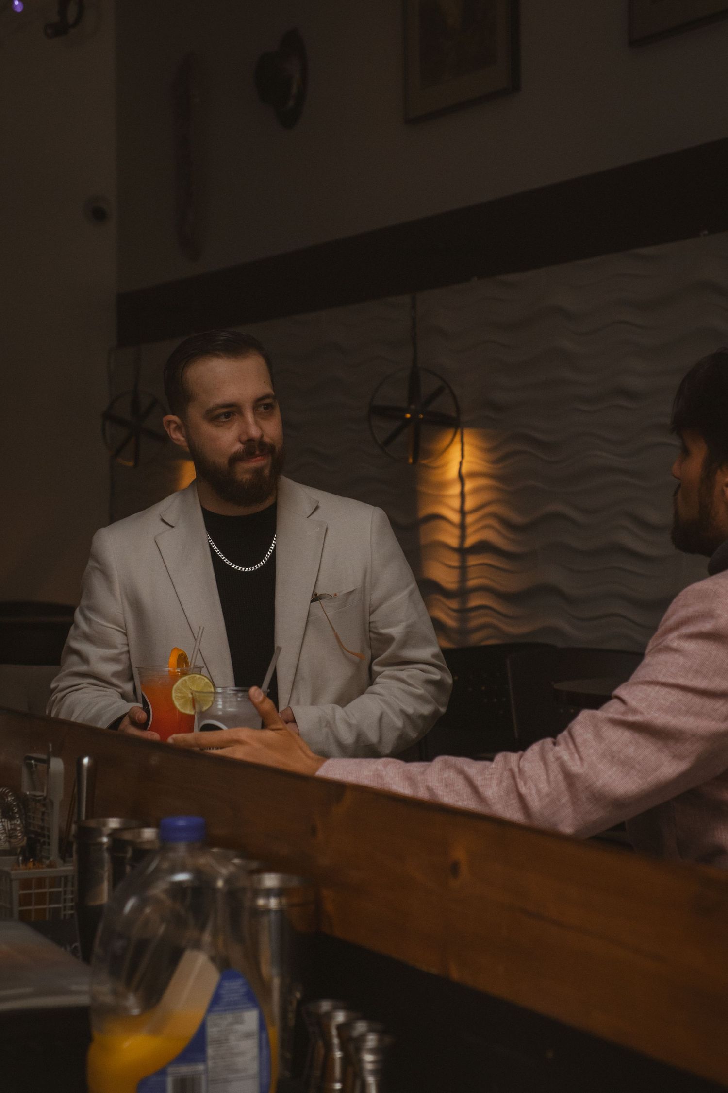 Friends sharing drinks at a wooden bar counter in an ambient setting.