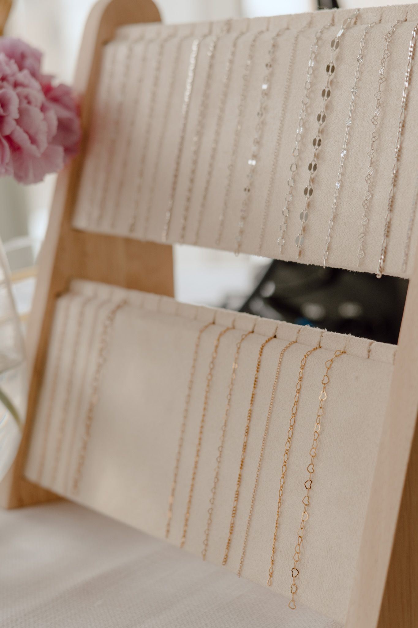Close-up of organized jewelry chains hanging on white display cards.