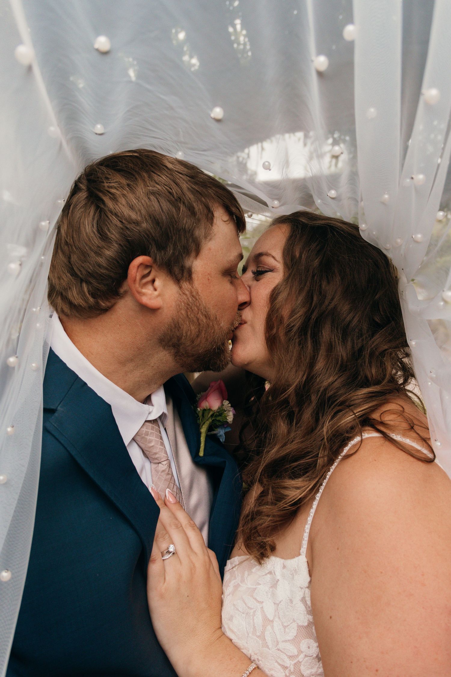 A romantic kiss moment captured against a white backdrop with twinkling lights.