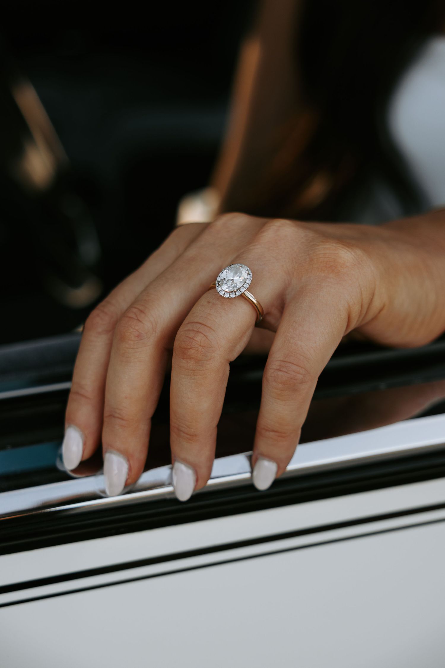 Close-up of hands playing piano keys with an elegant engagement ring sparkling in the light.
