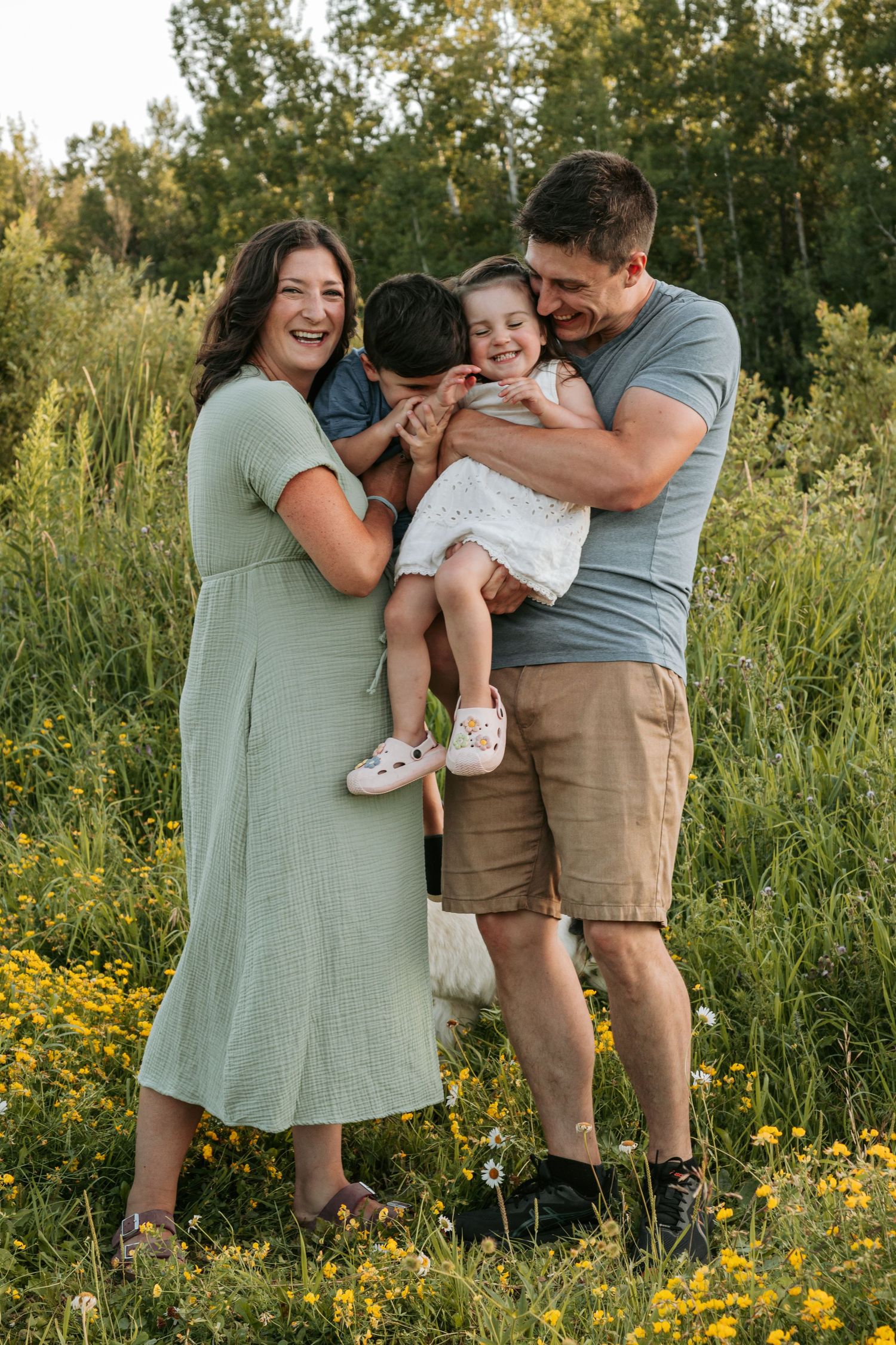 Family portrait session in a field of yellow wildflowers at sunset.
