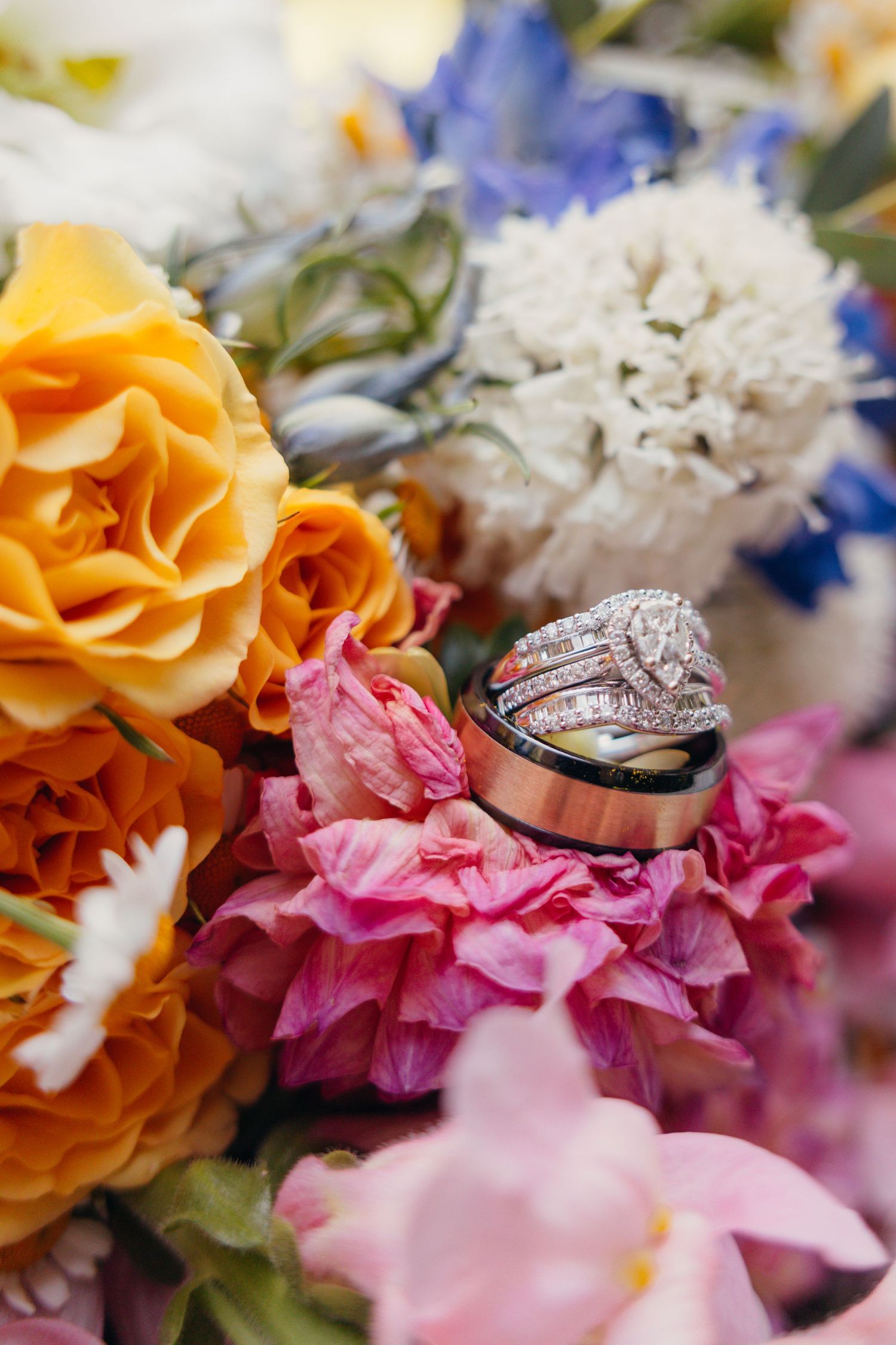 Diamond wedding rings nestled among pink, orange, and white flowers.