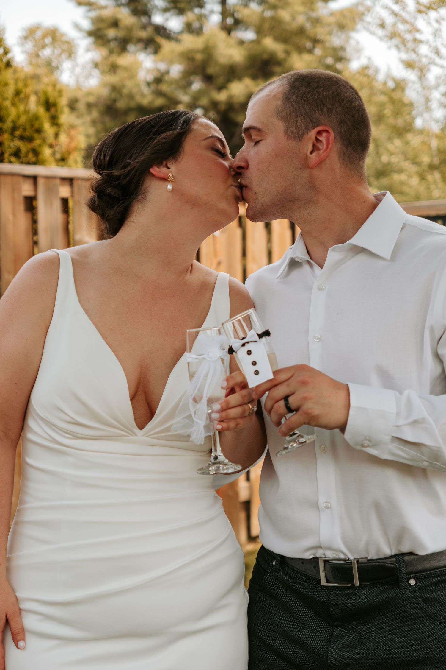 A romantic wedding moment captured as the couple shares drinks and laughter outdoors.