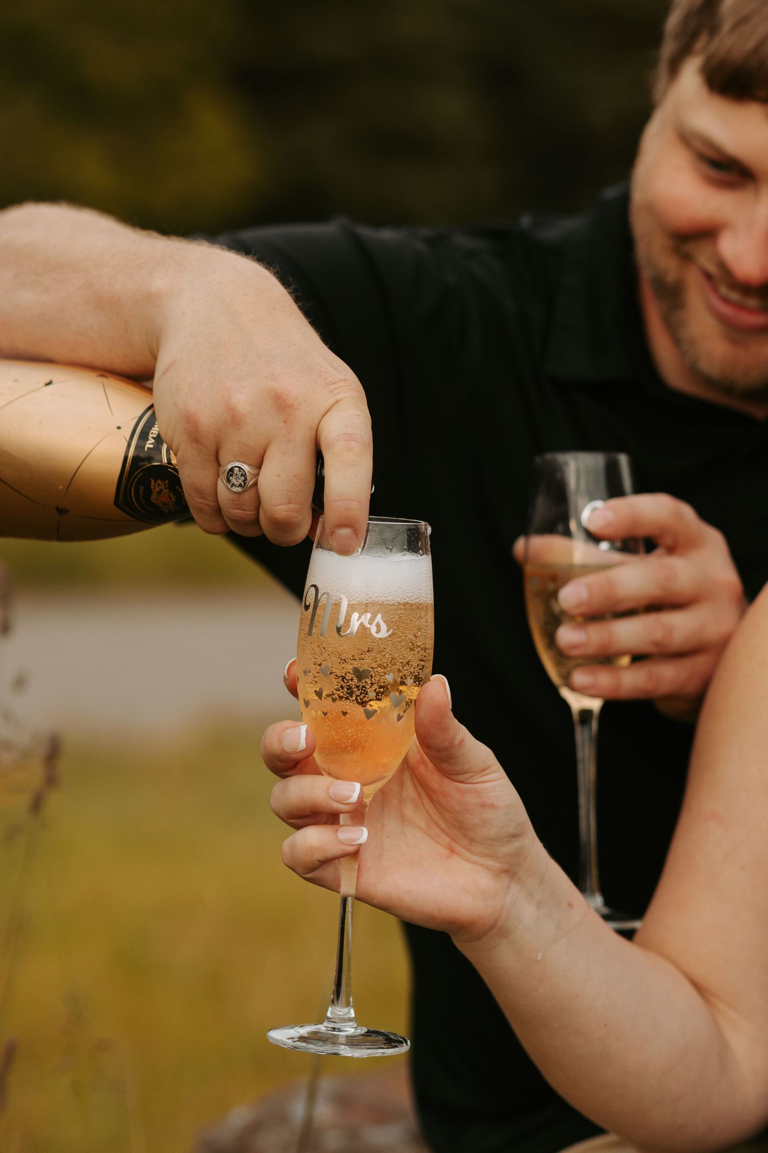 Hands toasting with champagne glasses marked 'Mr' and 'Mrs' against a golden sunset background.